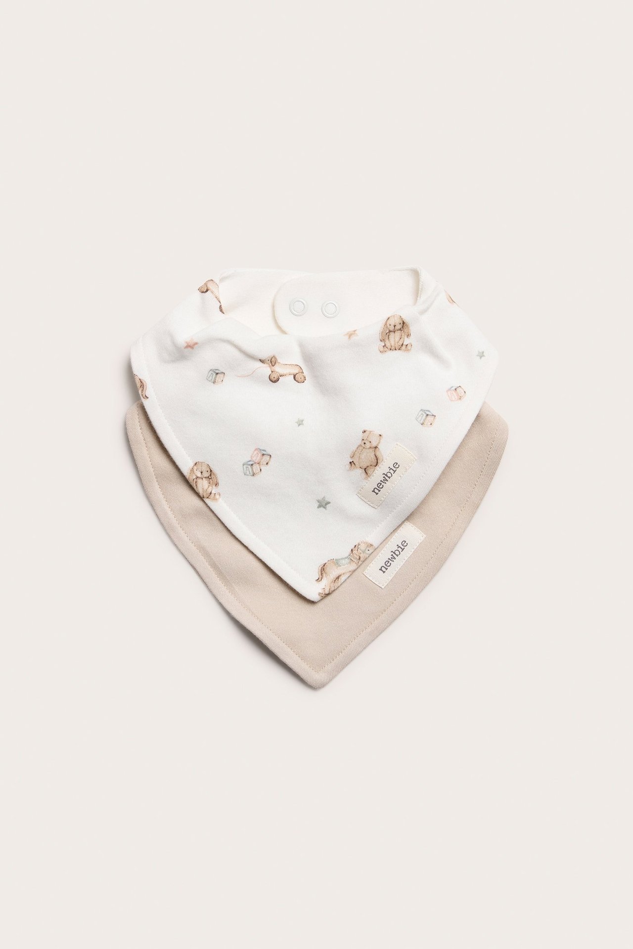 Toppvy av två trikådregglisar: en offwhite med nallemönster, en enfärgad beige, med tryckknappar.