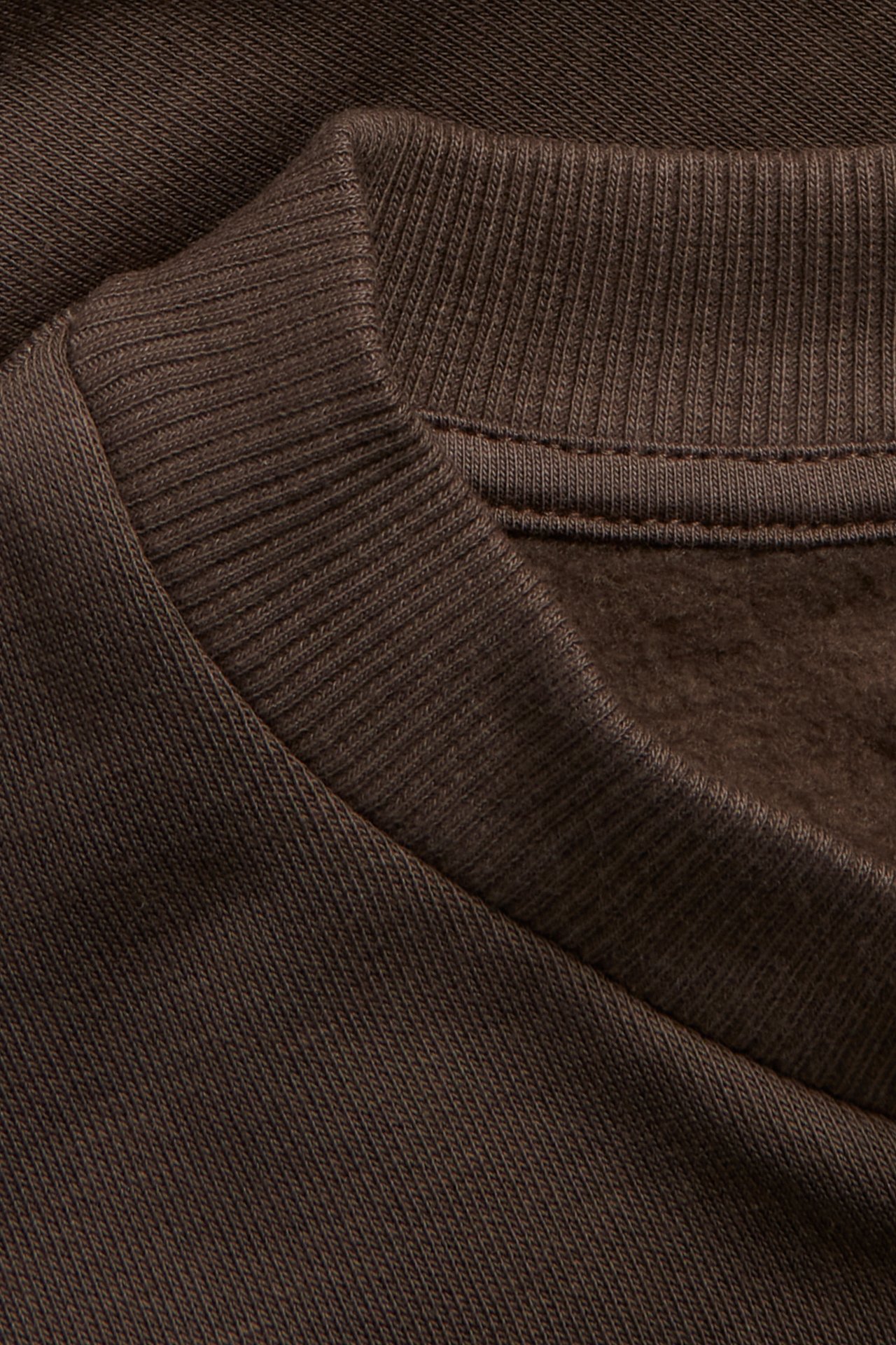 Zbliżenie na ciemnobrązową bluzę z okrągłym dekoltem, prążkowanym kołnierzem i miękkim wnętrzem.