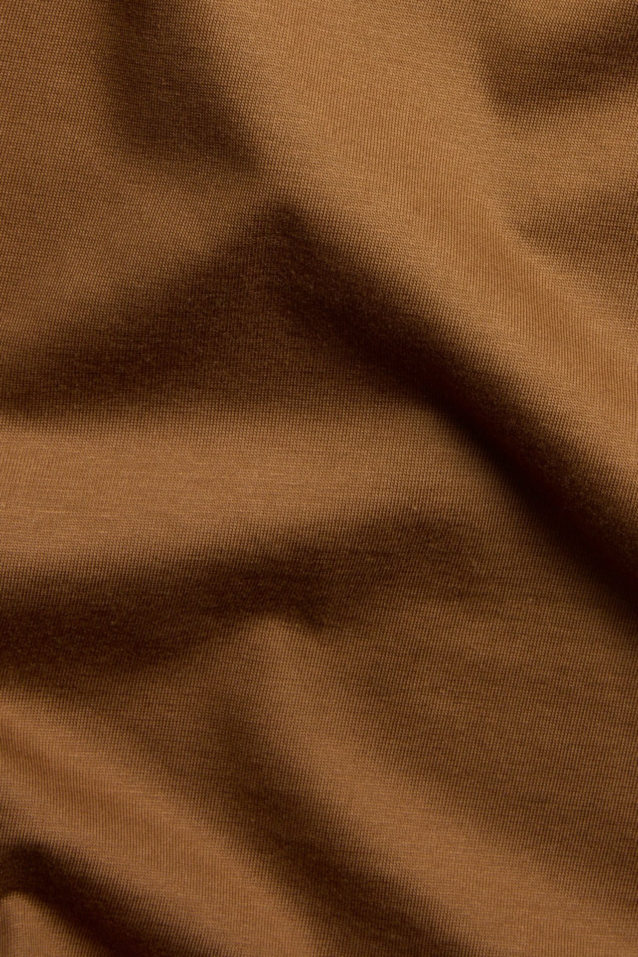 Zbliżenie na brązowy, jednolity materiał męskiego t-shirtu z bawełny organicznej.