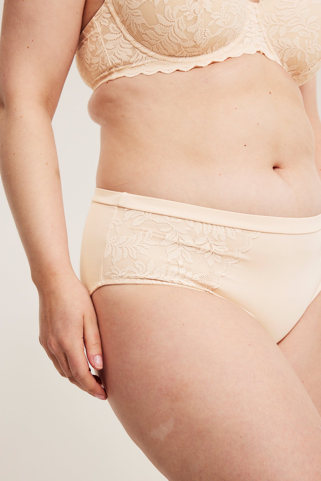 Närbild på kvinna i ljusrosa brieftrosa med spets och matchande spetsbehå.