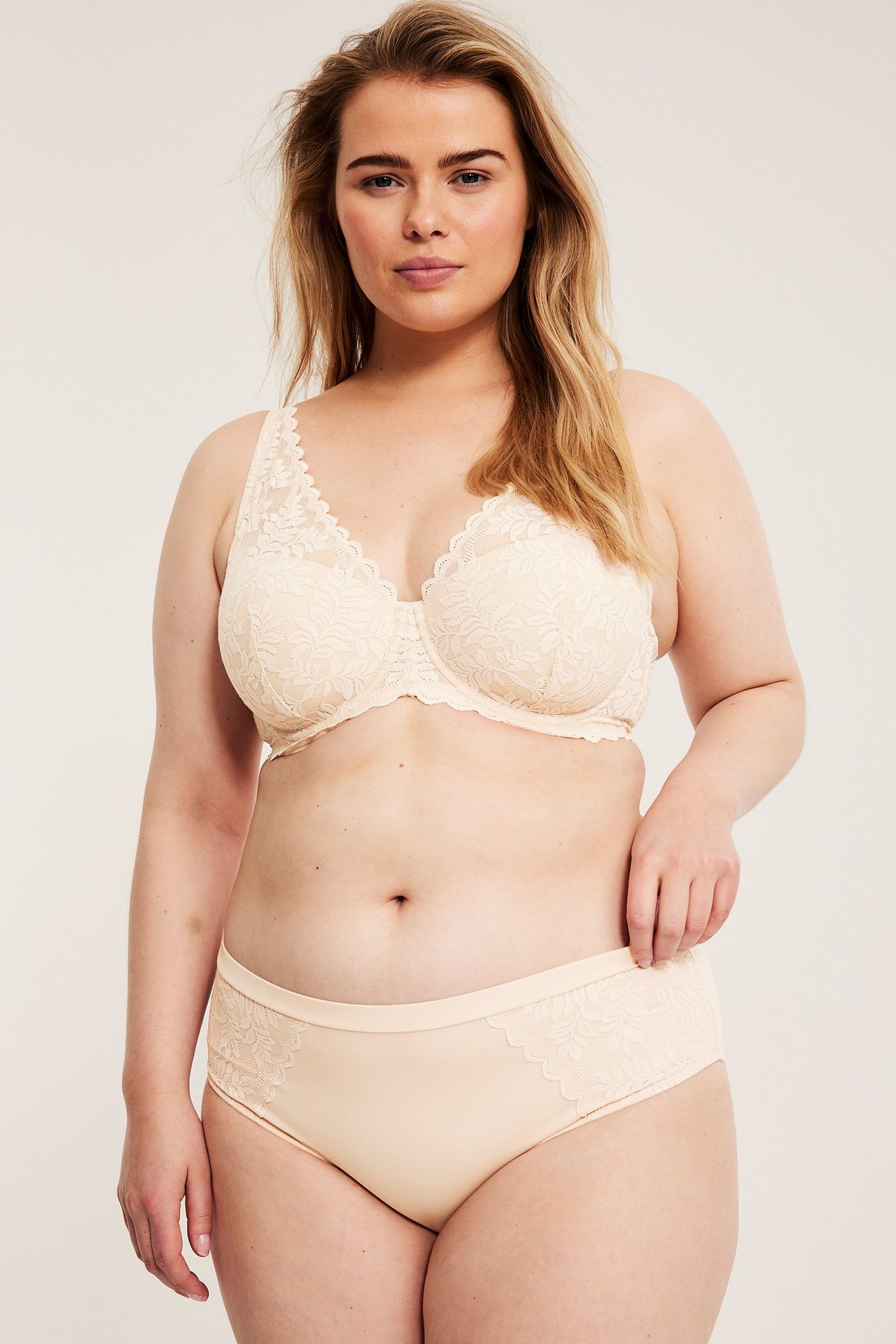 Edestä, nainen yllään vaaleanpunaiset mikrokuituiset pitsialushousut ja yhteensopivat pitsiliivit.