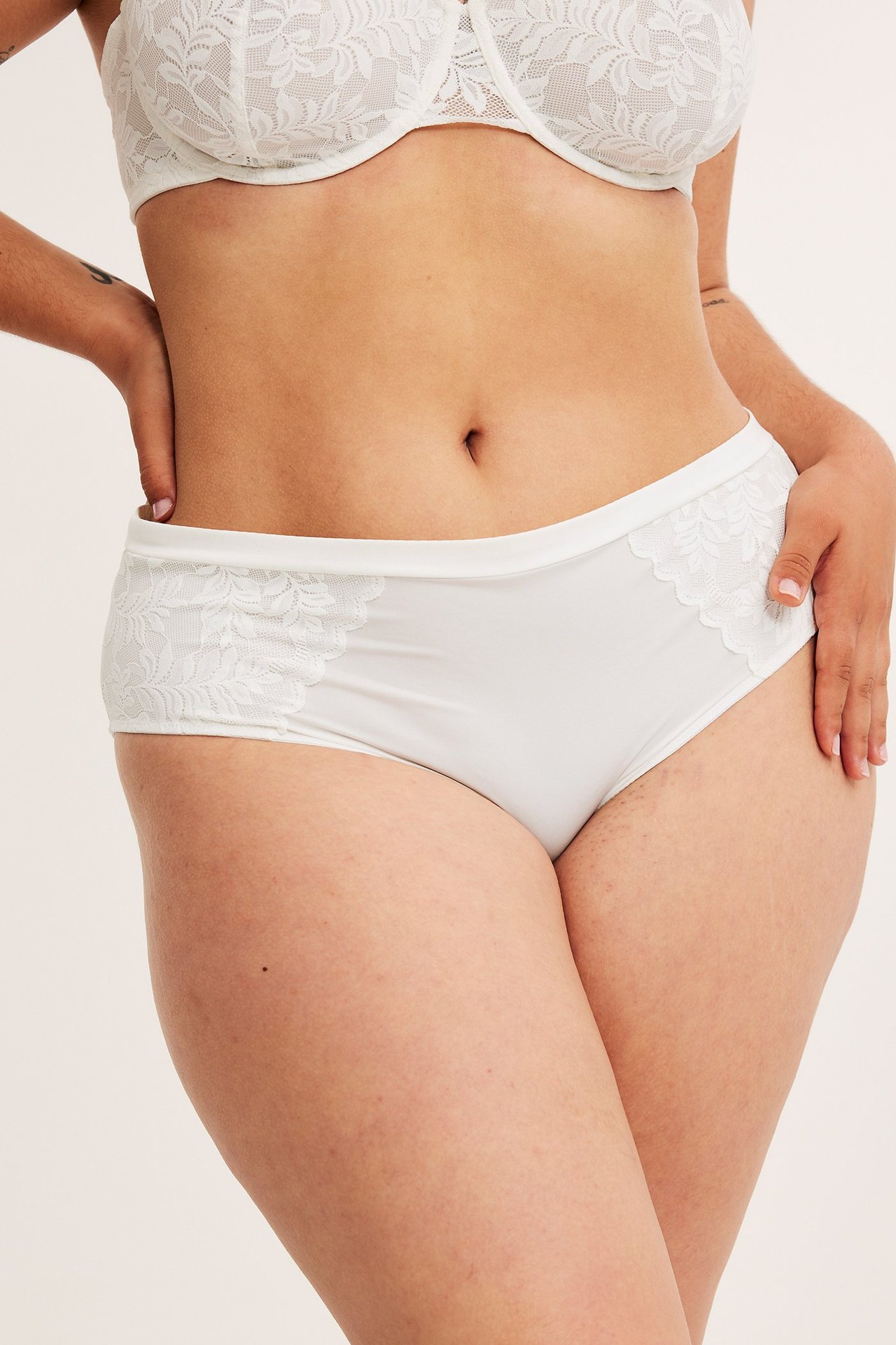 Frontbilde av en kvinne i offwhite blonde-briefs og matchende blonde-BH.