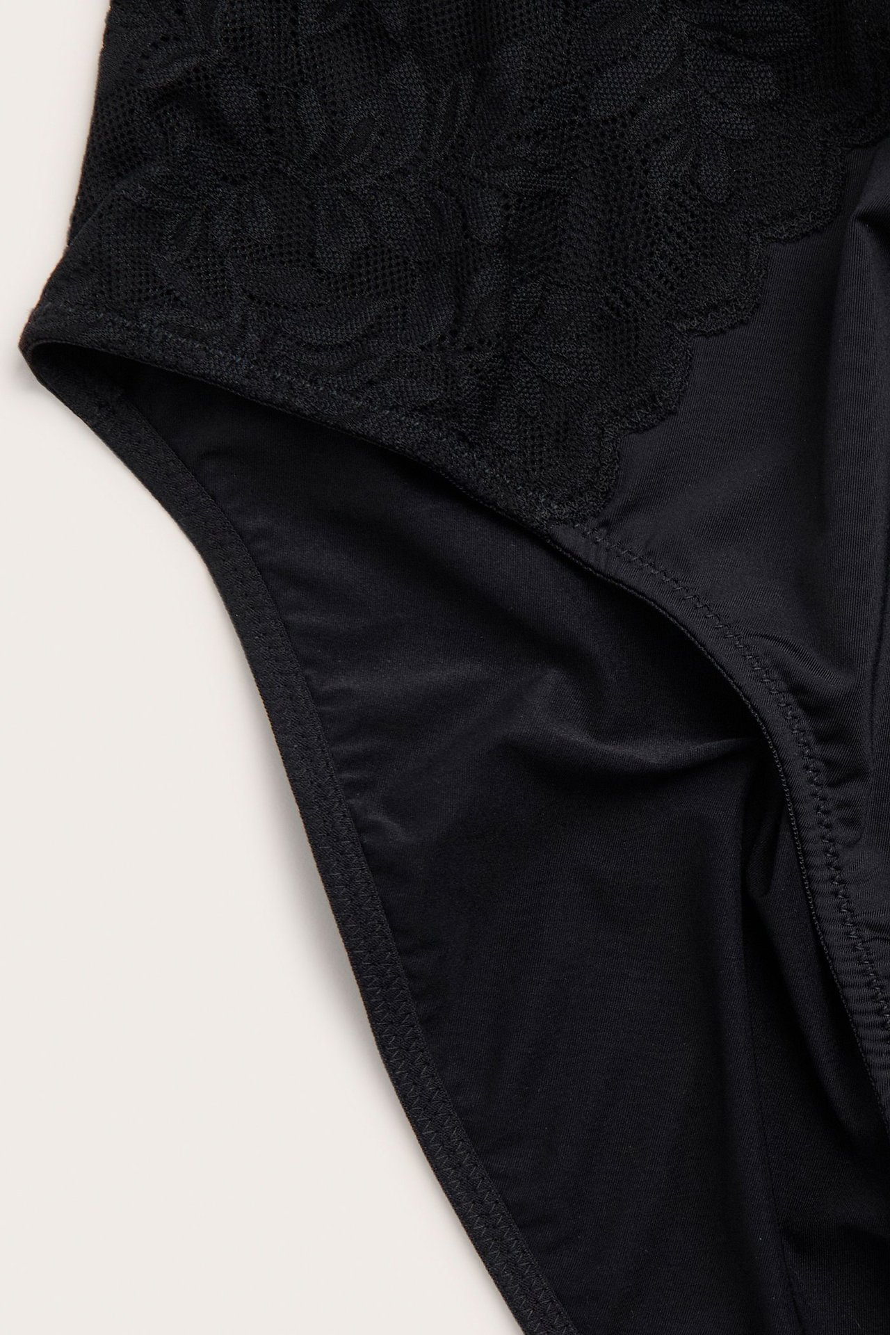 Zbliżenie czarnych majtek z mikrofibry z delikatnymi koronkowymi aplikacjami i elastycznym pasem.