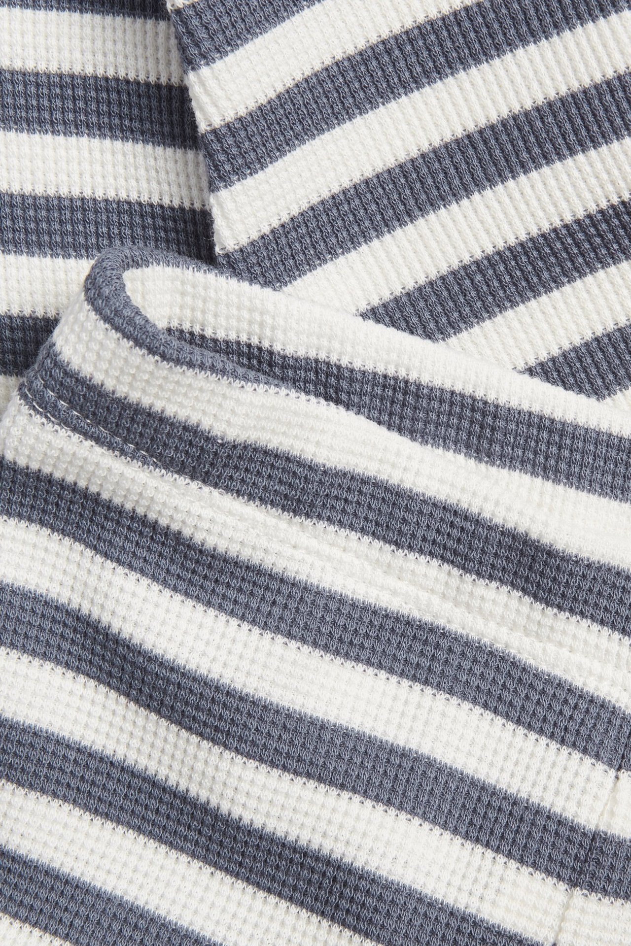 Zbliżenie na niebiesko-biały, prążkowany materiał waflowy legginsów niemowlęcych.