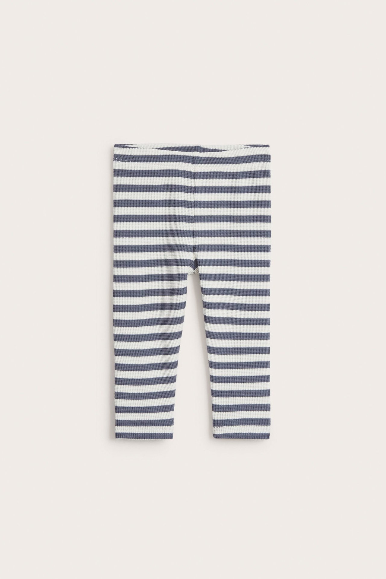 Widok z przodu niebiesko-białych, prążkowanych legginsów niemowlęcych z waflowej dzianiny z gumką w pasie.