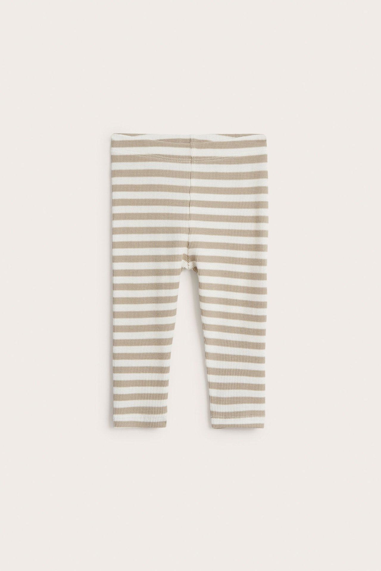 Frontvisning av baby-leggings i beige og hvitt med striper og vaffelstrikk.
