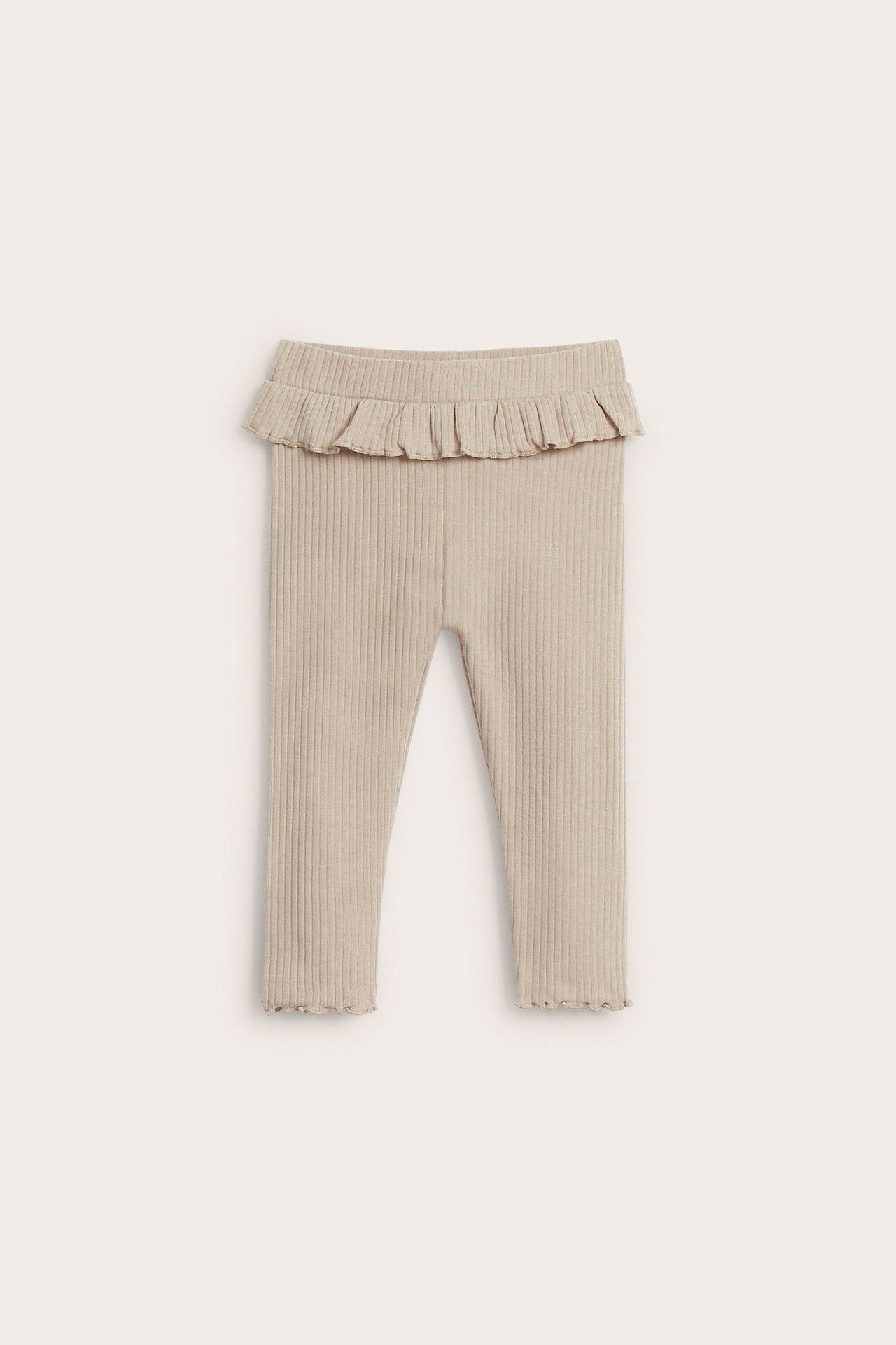 Frontvisning av beige ribbestrikkede baby-leggings med volangdetalj i midjen.