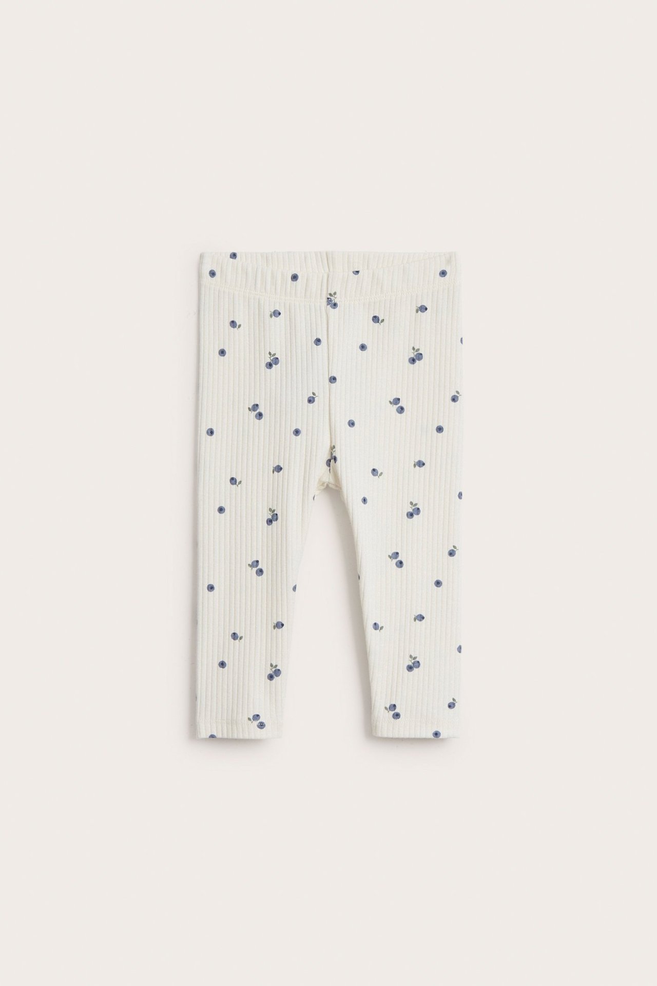 Forfra: Offwhite ribbestrikkede baby leggings med blått blåbærmønster.