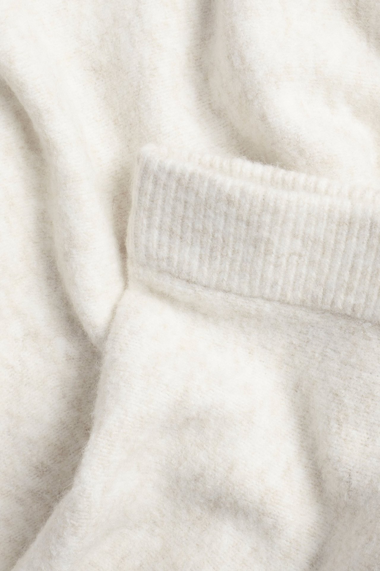 Zbliżenie jasnobeżowej dzianinowej spódnicy z elastycznym pasem.