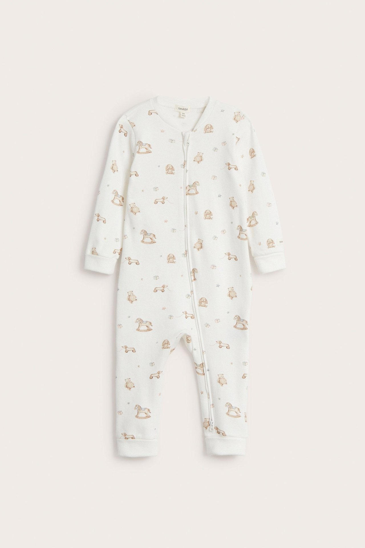 Frontvy av en offwhite bomulls-babypyjamas med leksaksmönster och tvåvägsdragkedja.