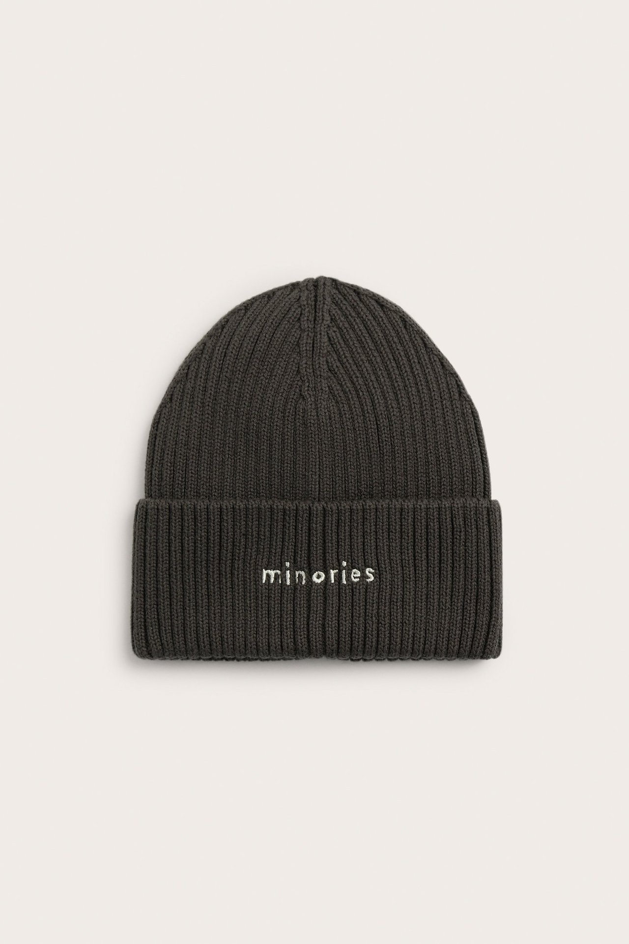 Edestä näkymä tummanruskeasta ribatusta puuvillapiposta, jossa taitettu reuna ja valkoinen "minories" kirjonta.