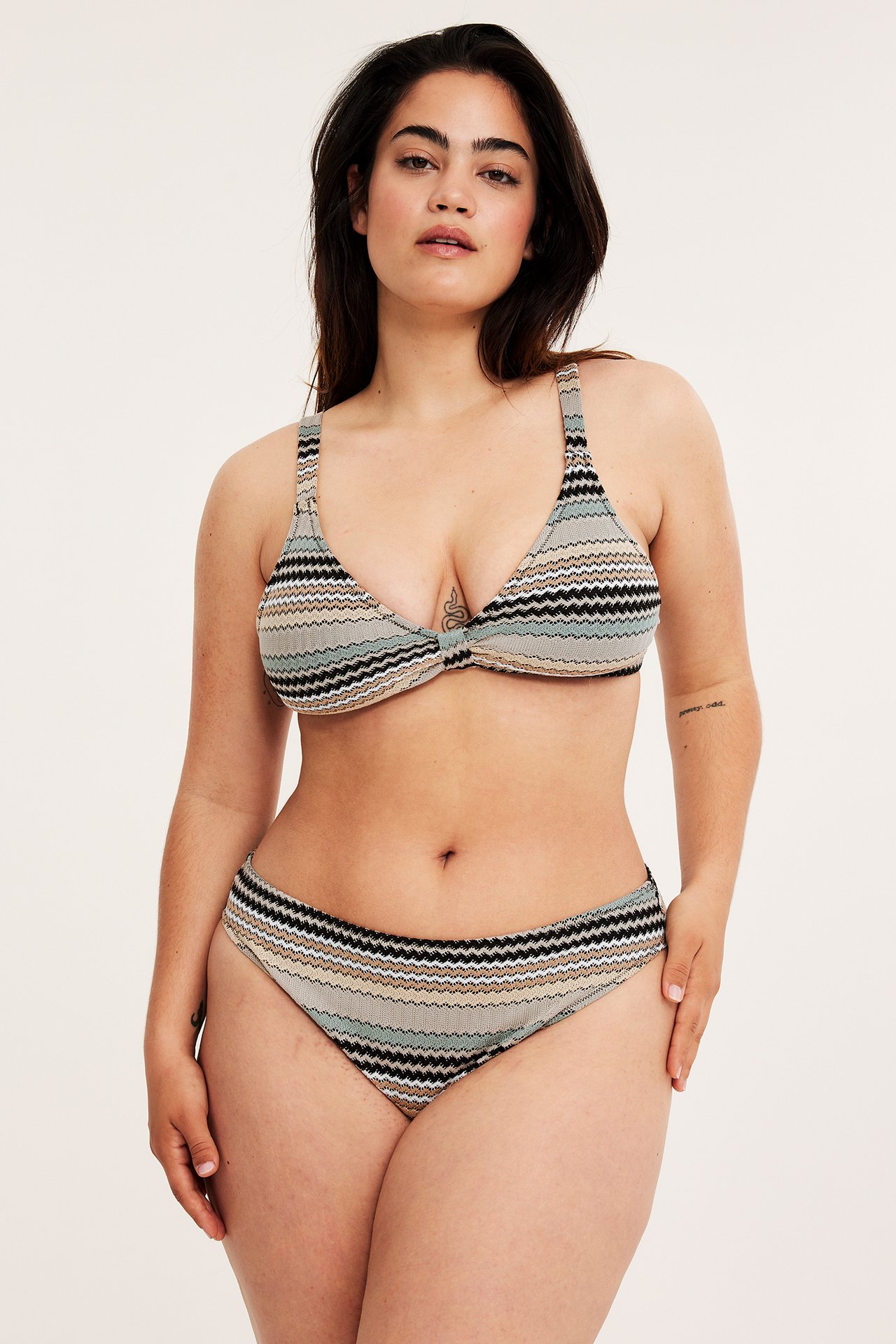 Framifrån: kvinna i mörkbeige randig bikini-bh med vriden front och matchande bikinitrosa.