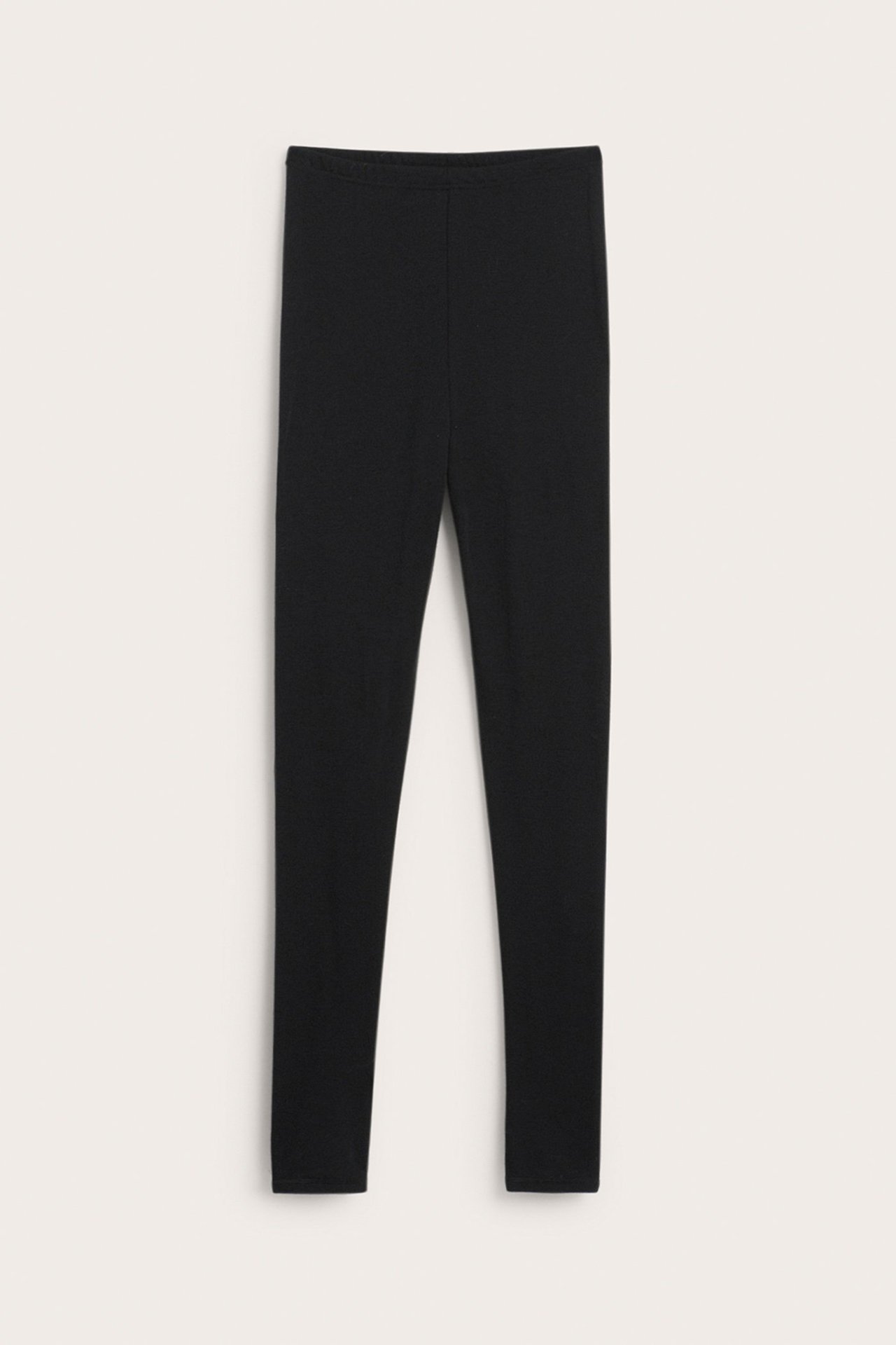 Framifrån, svarta leggings i merinoull med resår i midjan, plattlagda.