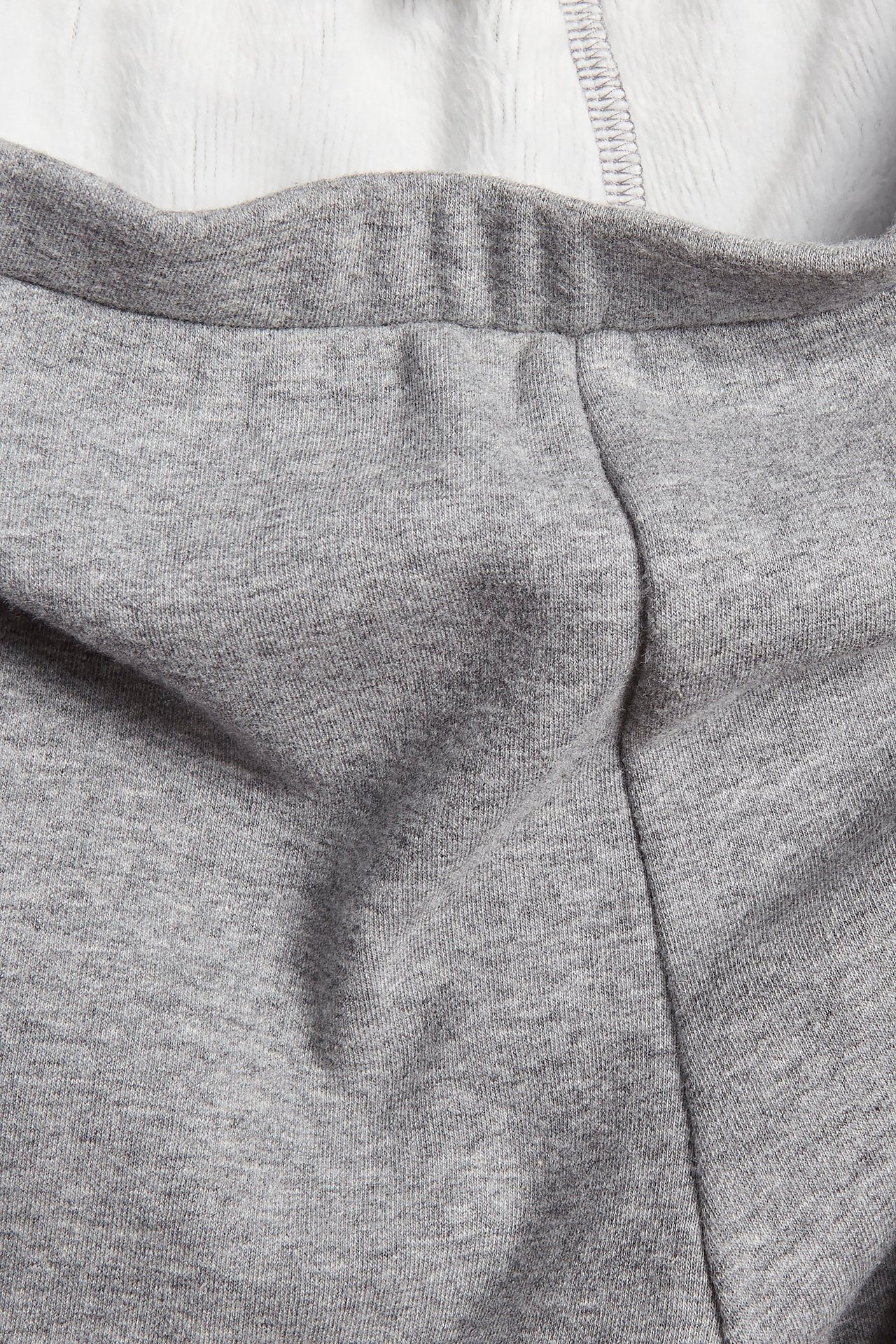 Zbliżenie na jasnoszare melanżowe legginsy z elastycznym pasem i miękkim, szczotkowanym białym wnętrzem.