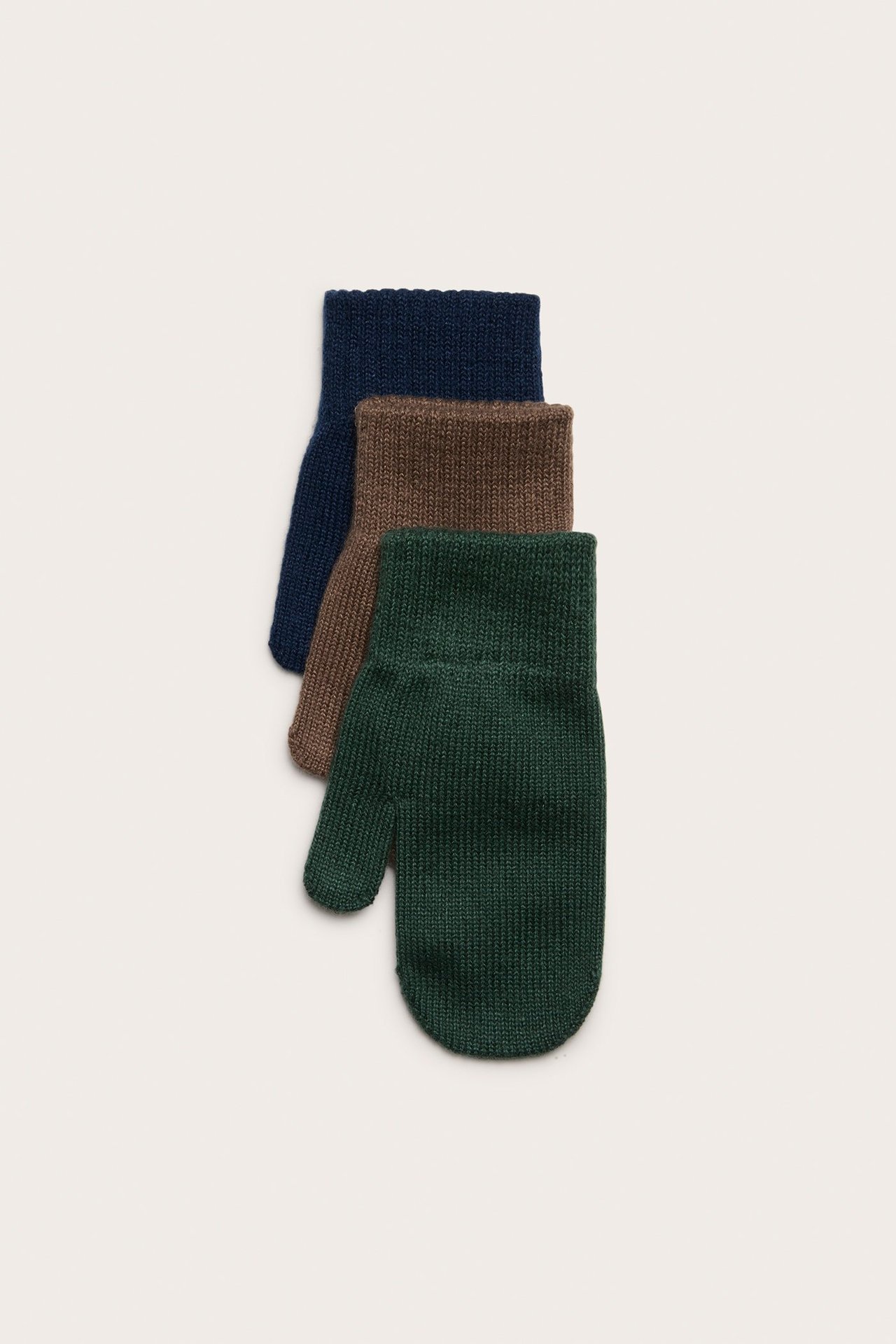 Trzy pary dziecięcych dzianinowych rękawiczek: ciemnozielone, brązowe i granatowe, widok z góry.
