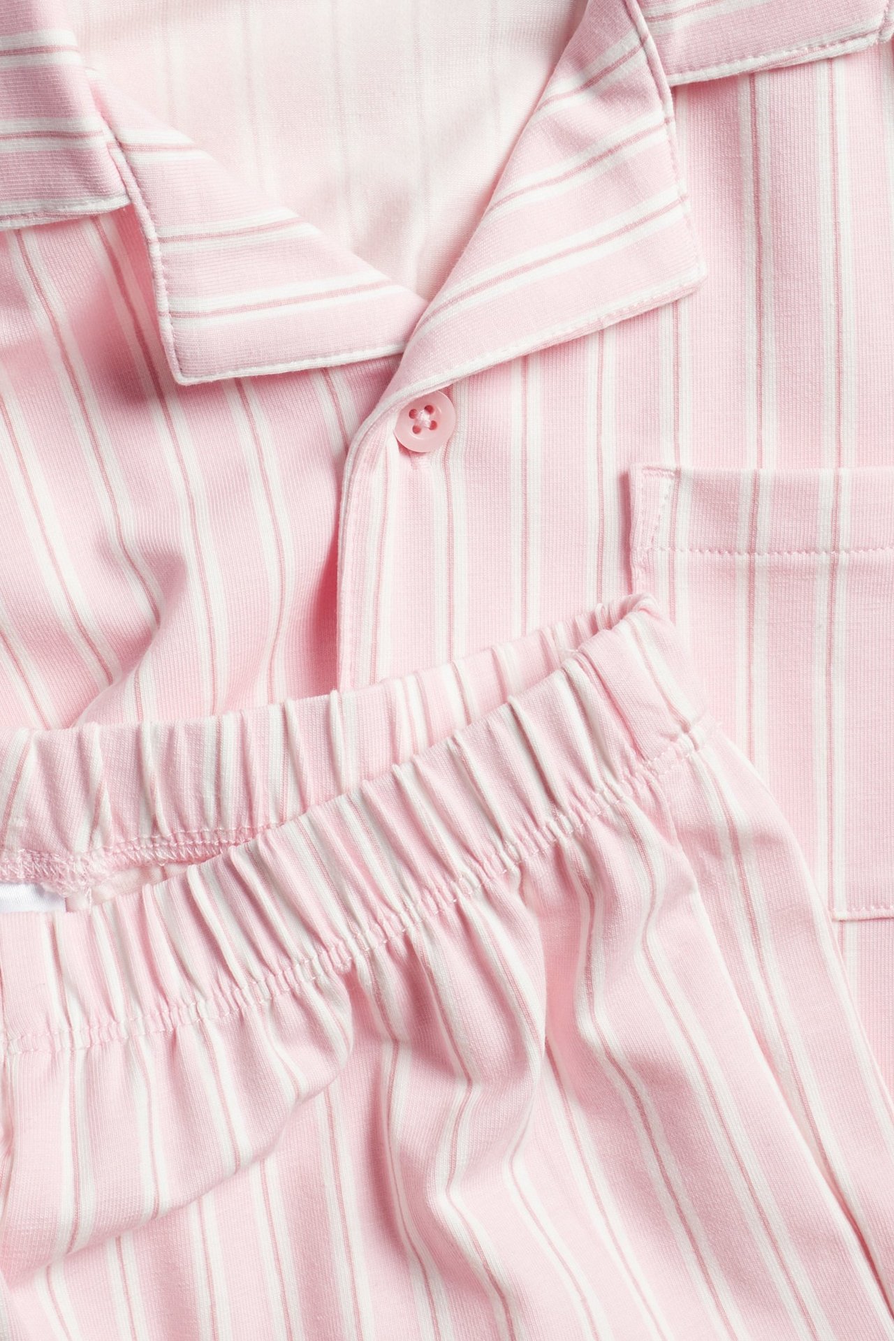 Zbliżenie różowo-białej piżamy w paski z dżerseju, z kołnierzykiem i elastycznym pasem spodni.