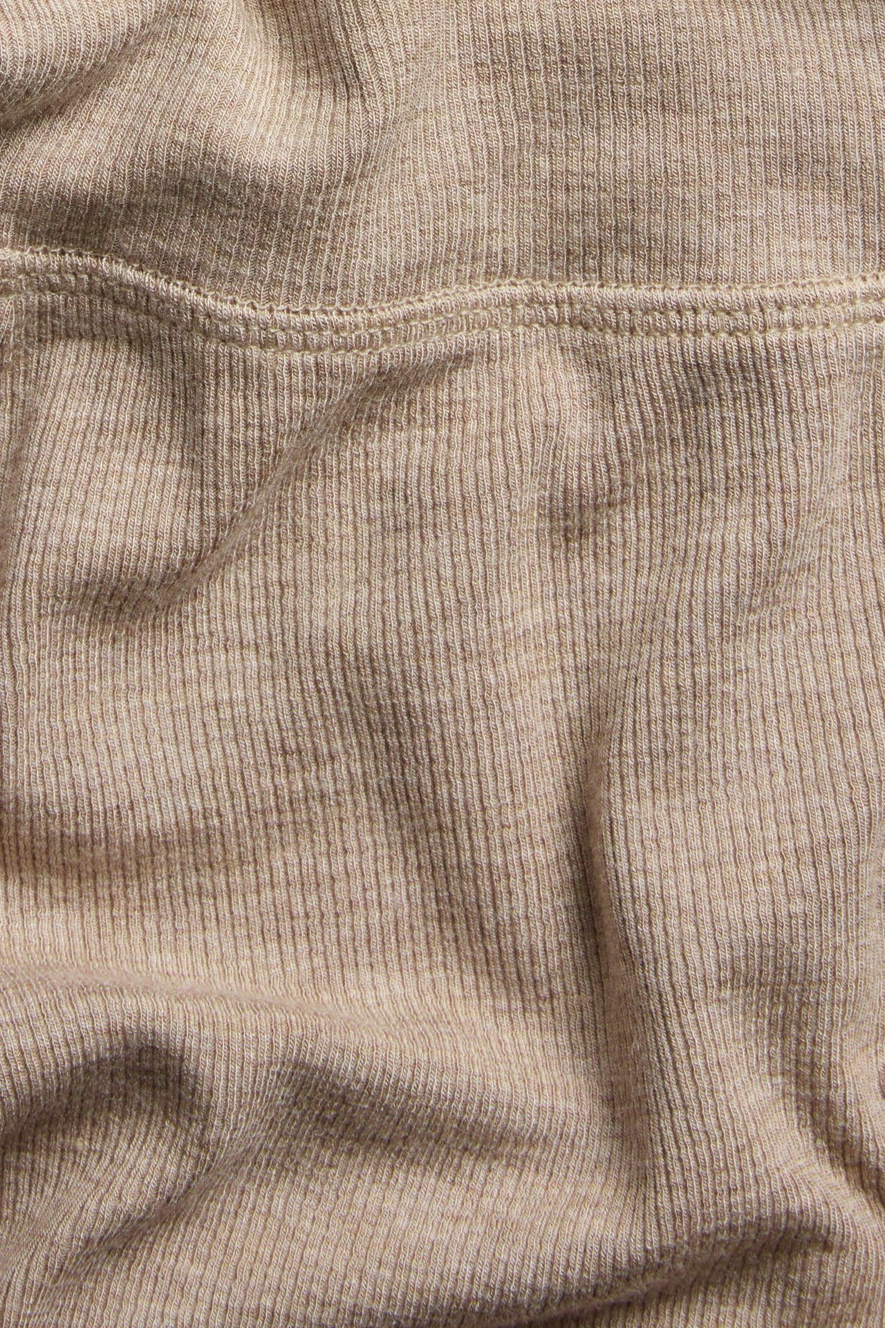 Zbliżenie beżowych, melanżowych, prążkowanych spodni piżamowych z mieszanki wiskozy ze szwem.