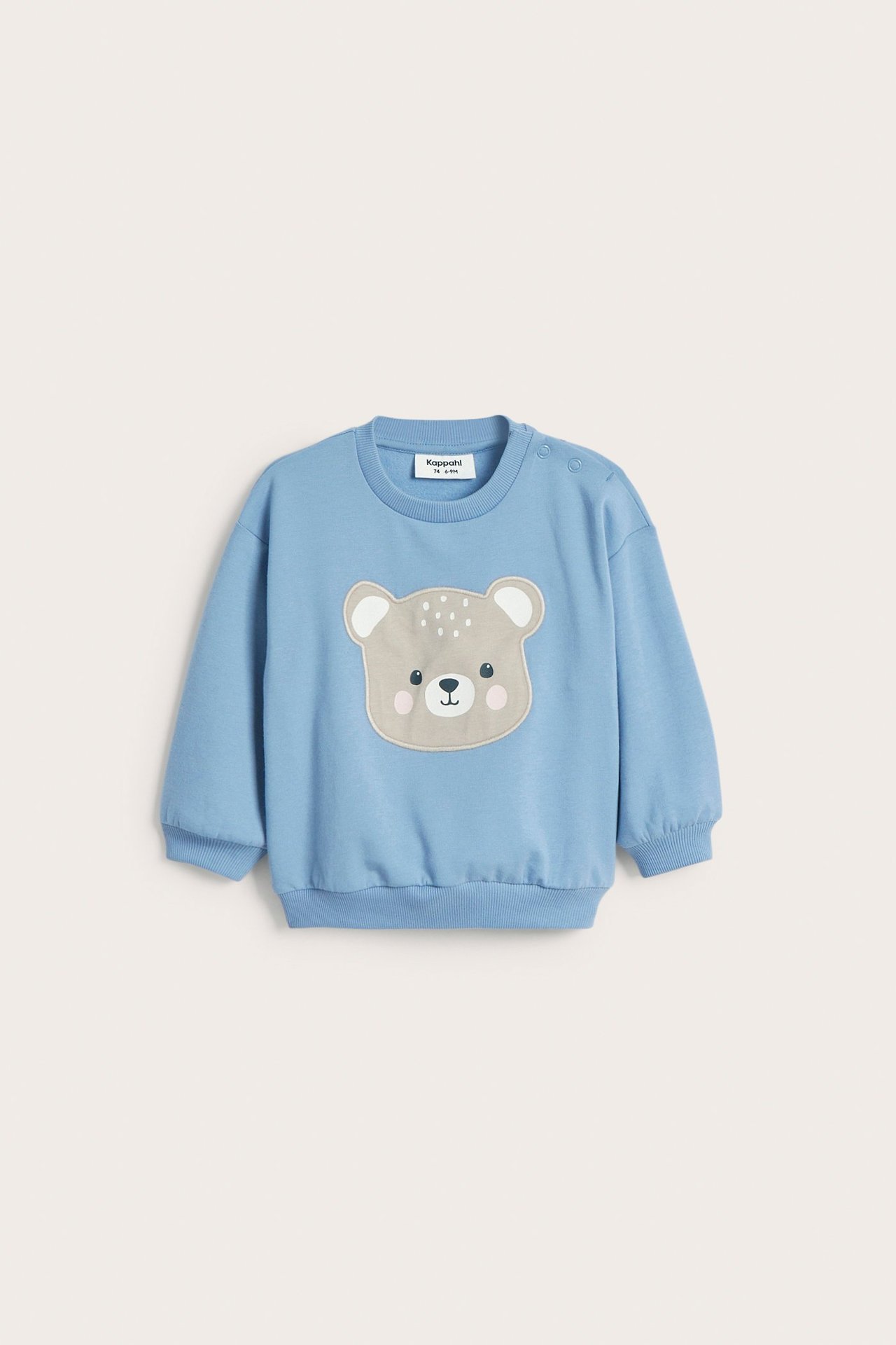 Widok z przodu niebieskiej bawełnianej bluzy niemowlęcej z aplikacją misia i napami na ramieniu.