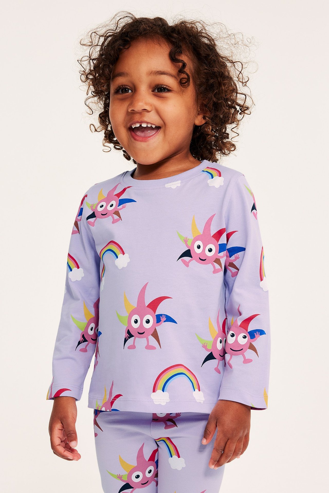Framifrån: Barn i lila långärmad t-shirt och matchande byxor med Babblarna-tryck.