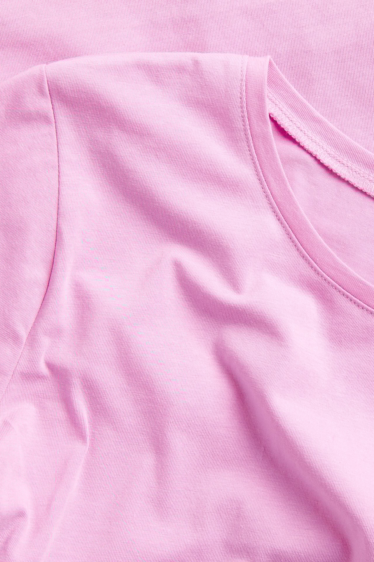 Zbliżenie różowego, krótkiego rękawa, podstawowego topu z okrągłym dekoltem, z mieszanki bawełny.