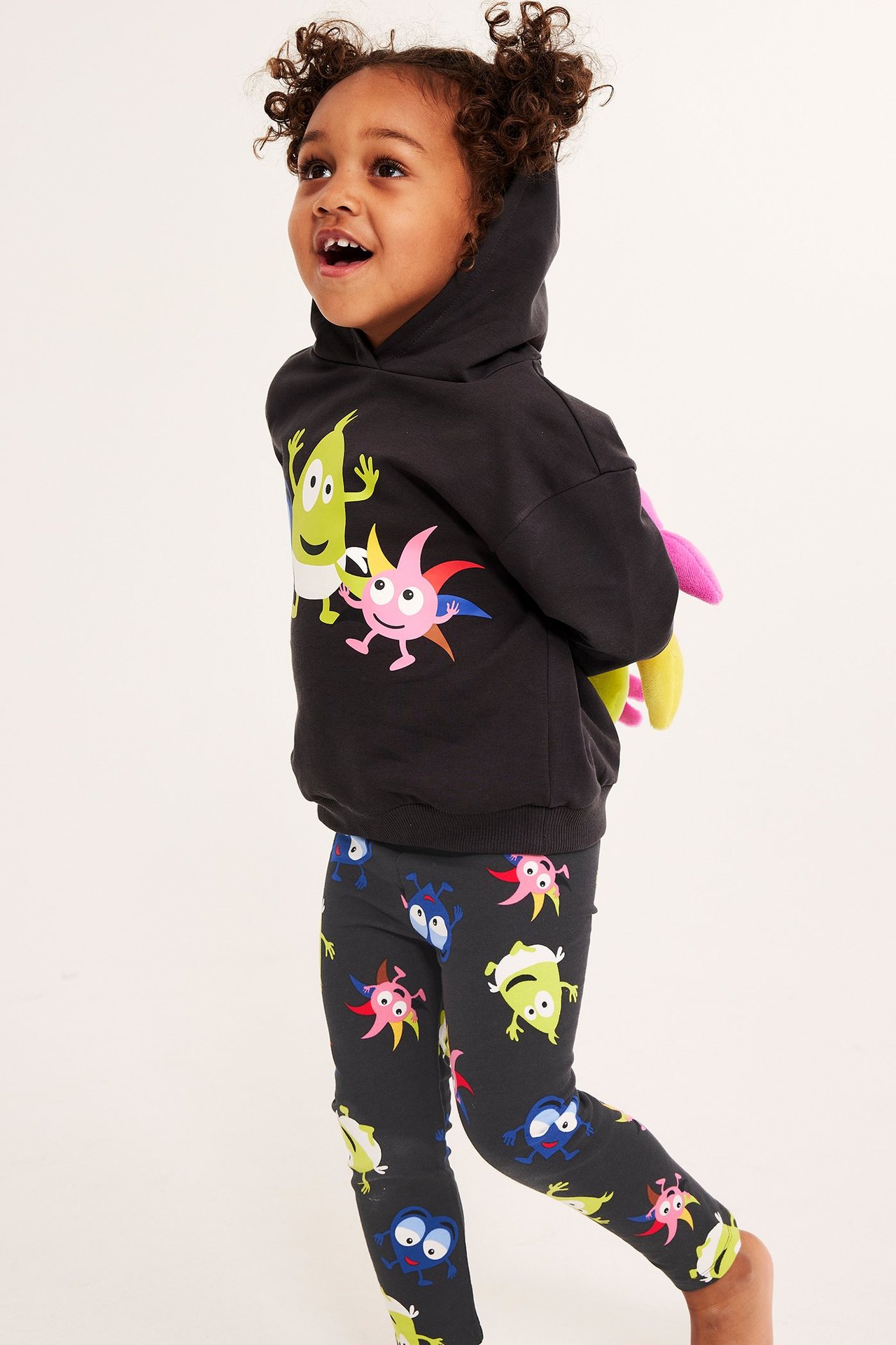 Ett barn bär svarta mönstrade Babblarna-leggings och en svart Babblarna-hoodie, framifrån.