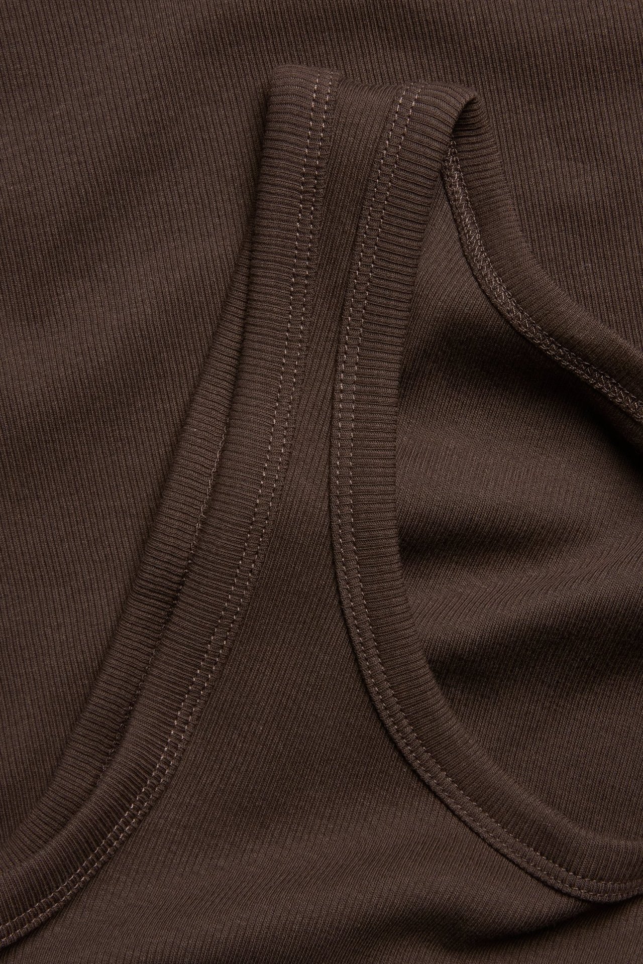 Zbliżenie na ciemnobrązowy prążkowany top, ukazujące wąską strukturę prążków i szwy.