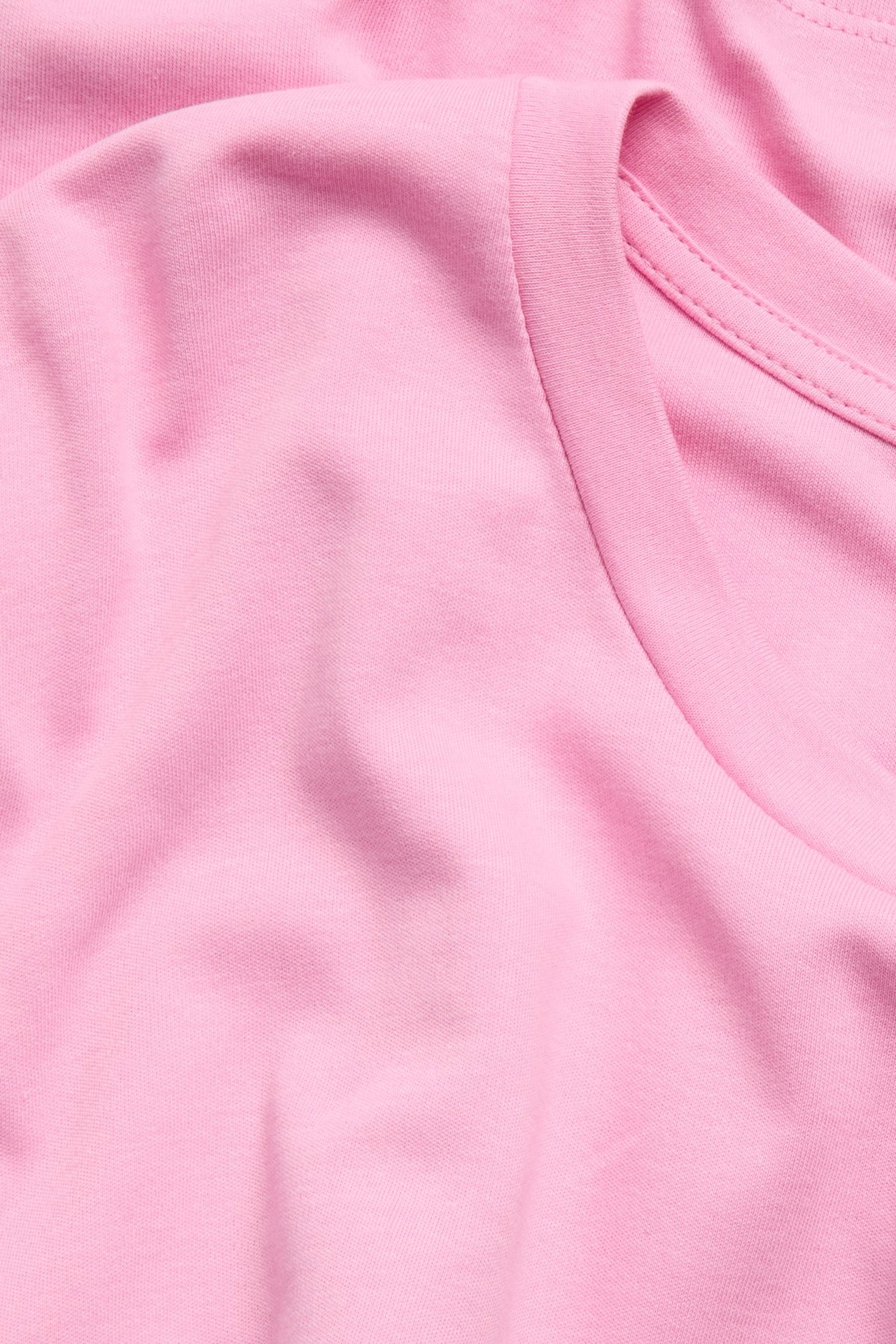 Zbliżenie różowego luźnego bawełnianego t-shirtu z długim rękawem, pokazujące fakturę materiału i dekolt.