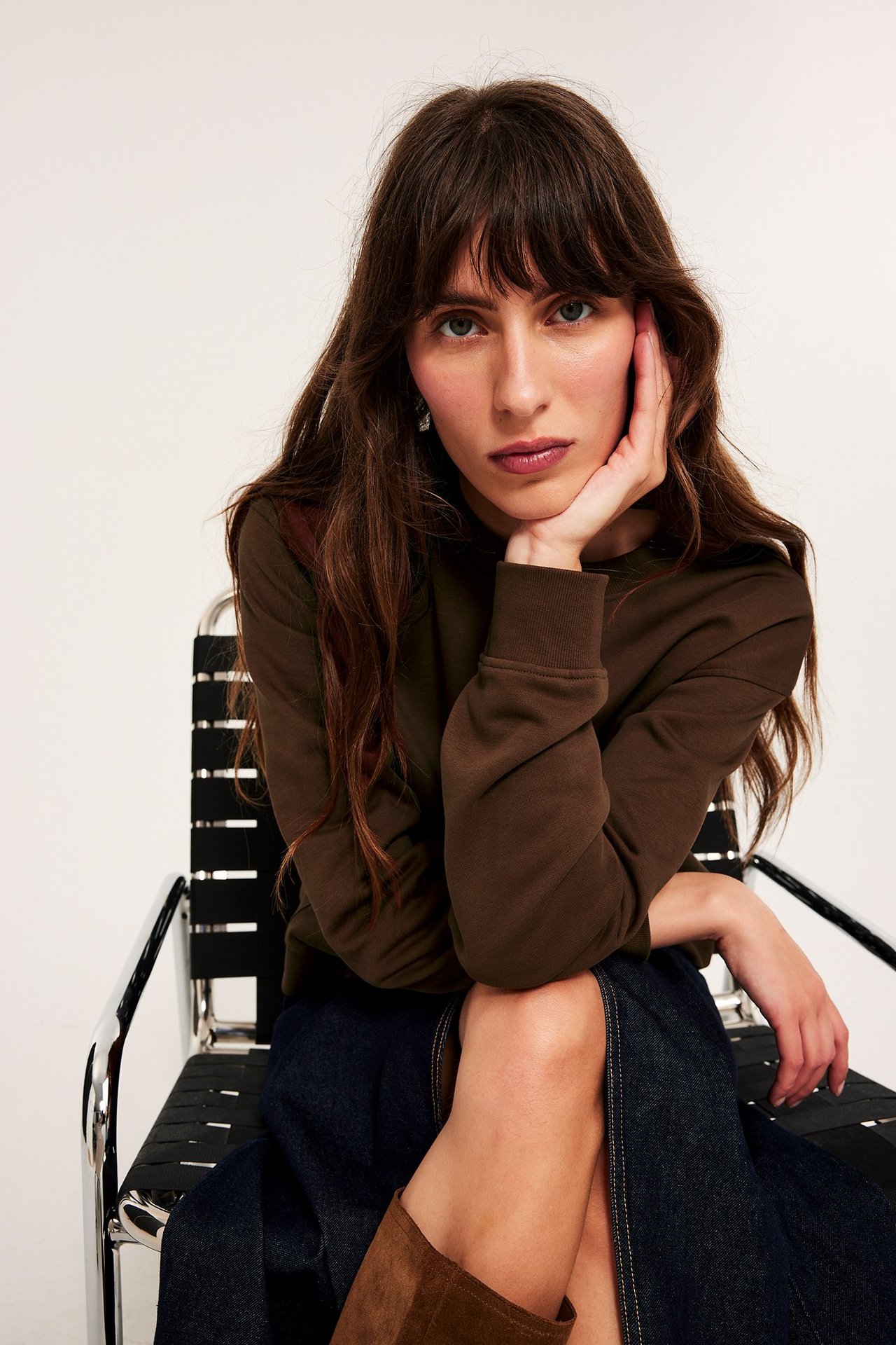 Edestä: Nainen ruskeassa collegepaidassa, tummansinisessä farkkuhameessa ja ruskeissa mokkasaappaissa.