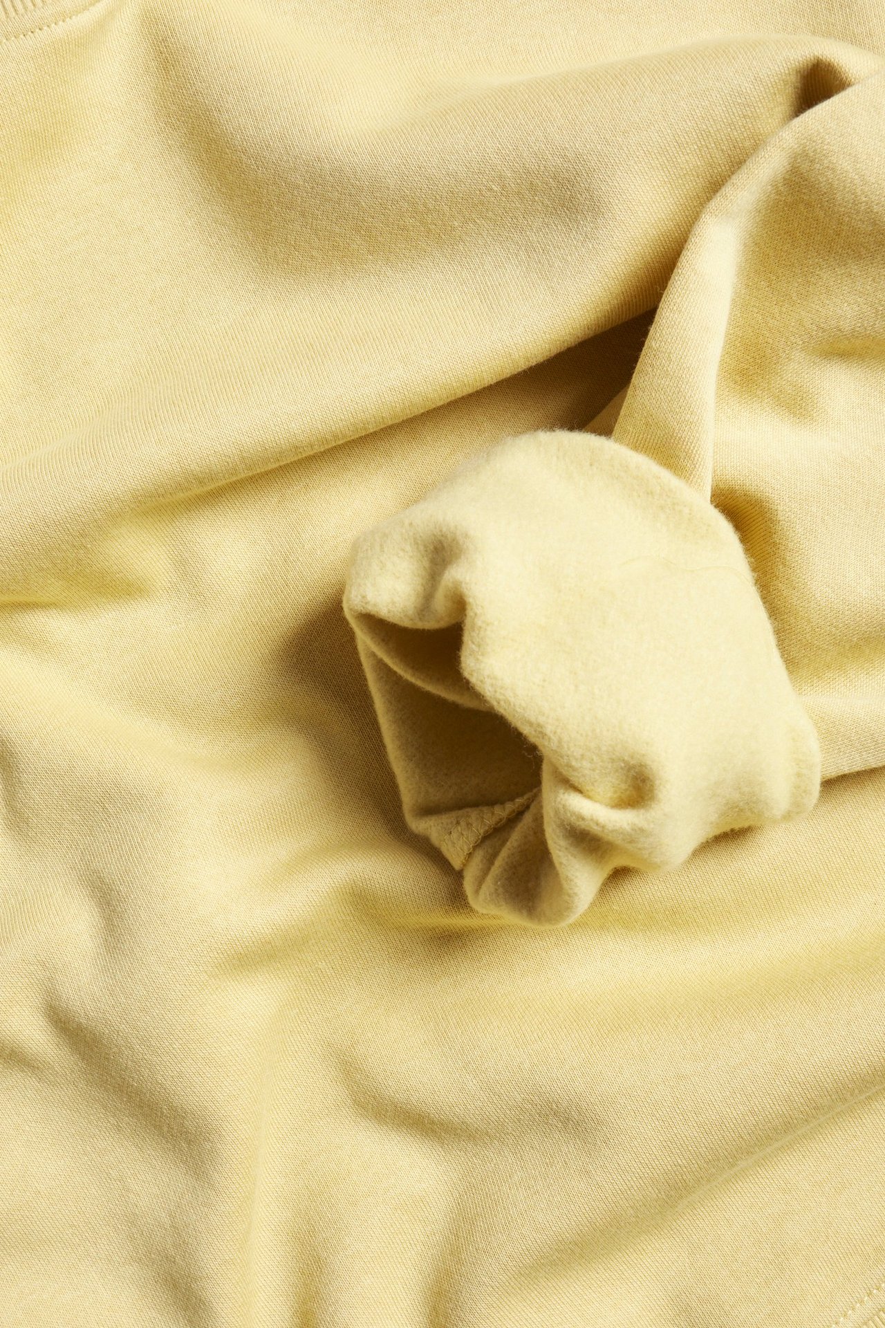 Zbliżenie na jasnożółtą bluzę z bawełny z domieszką, z prążkowanym mankietem.