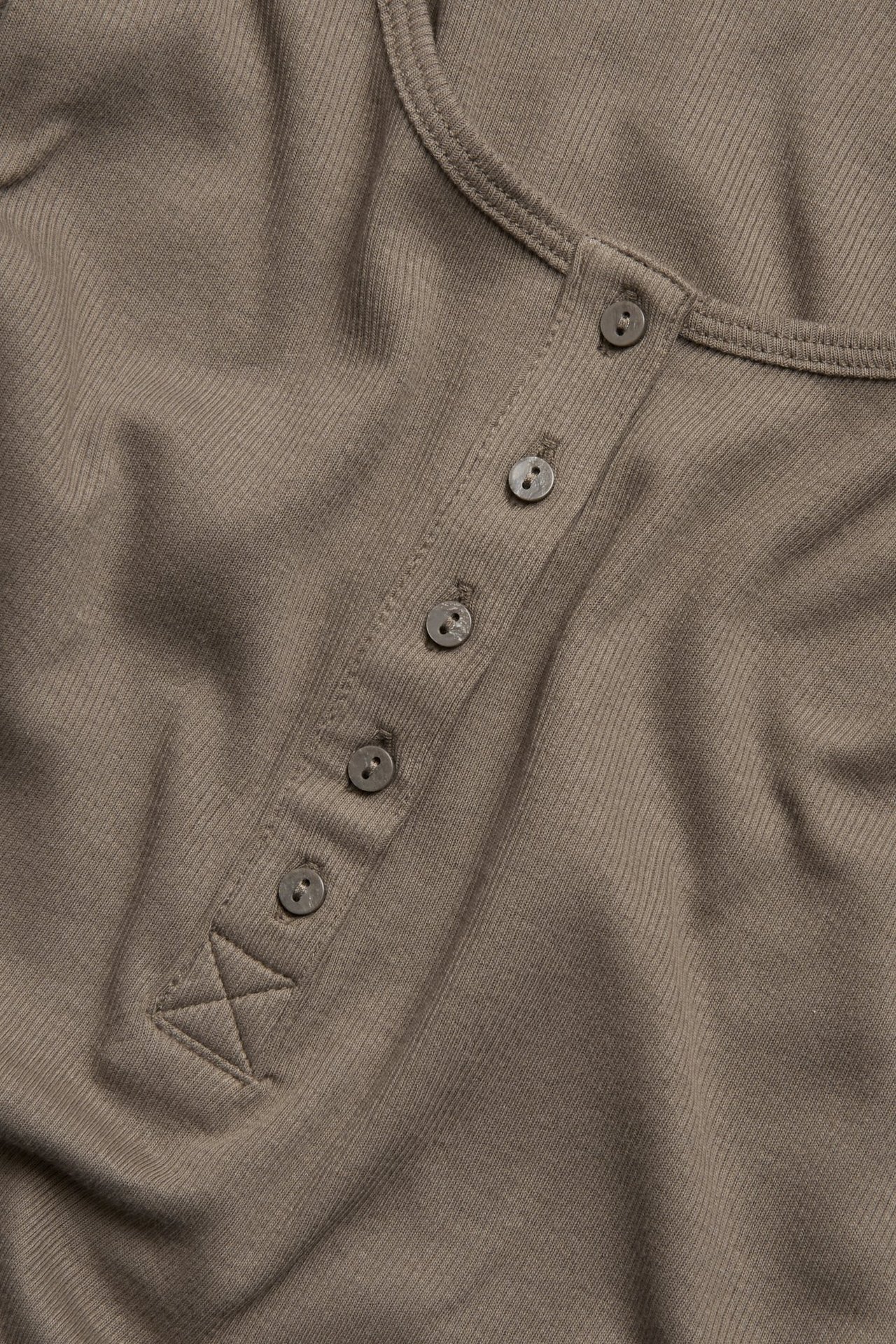Zbliżenie brązowego prążkowanego topu z listwą z czterema guzikami z przodu.
