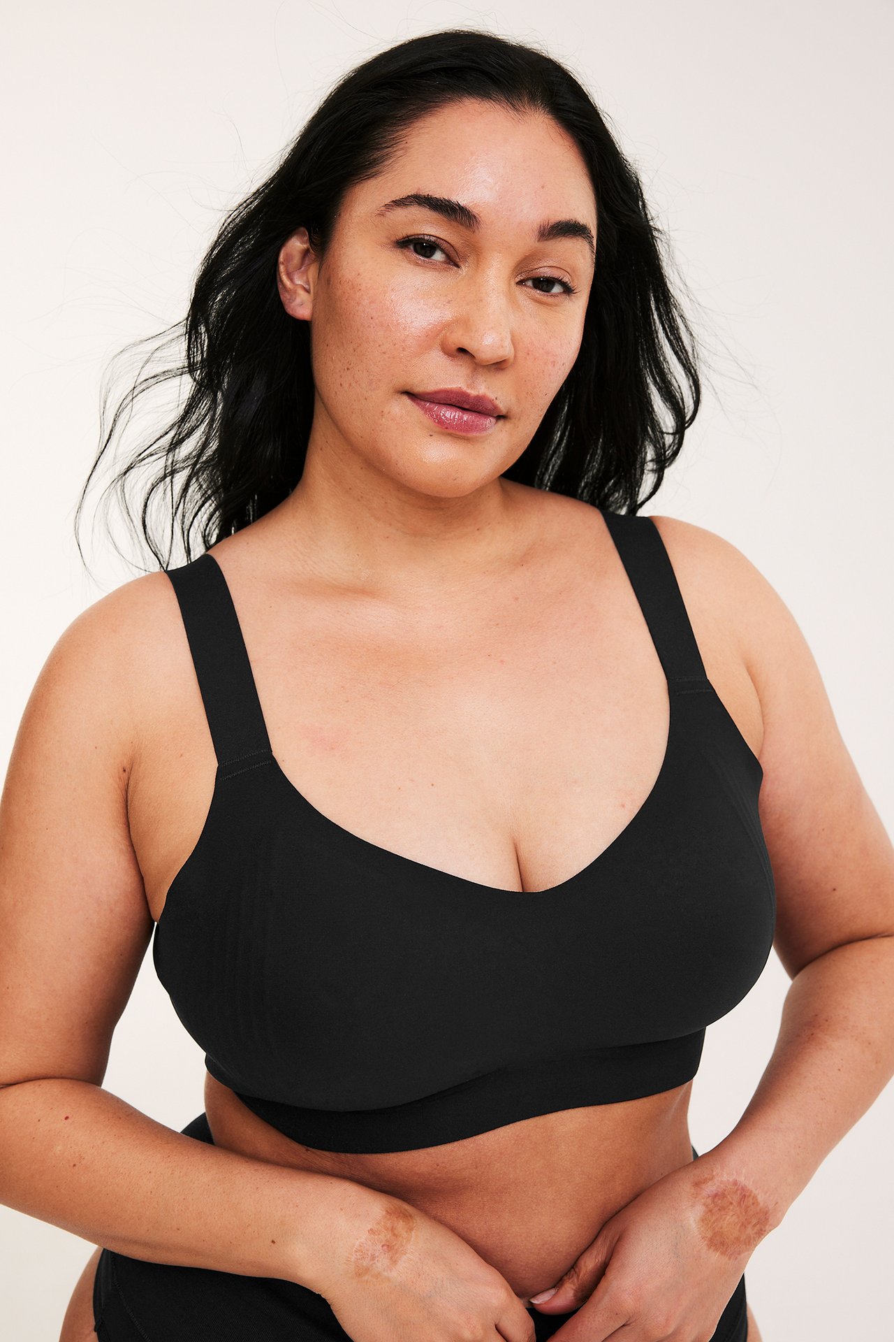 Kobieta z przodu w czarnym, bezfiszbinowym biustonoszu micro z szerokimi, regulowanymi ramiączkami i gładkim wykończeniem.