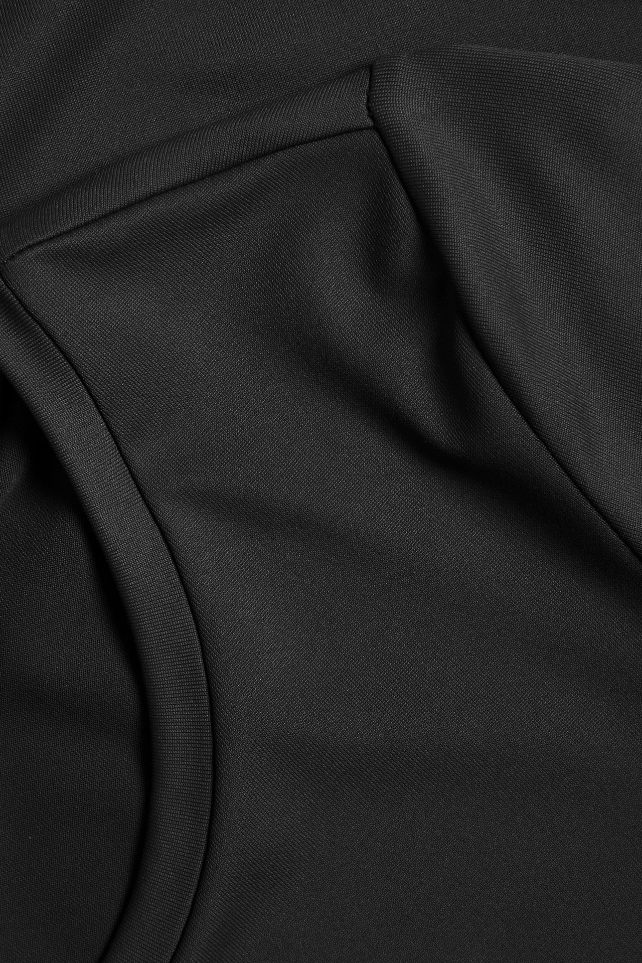 Zbliżenie czarnego, gładkiego T-shirtu, ukazujące teksturę tkaniny poliamidowo-elastanowej i szwy.
