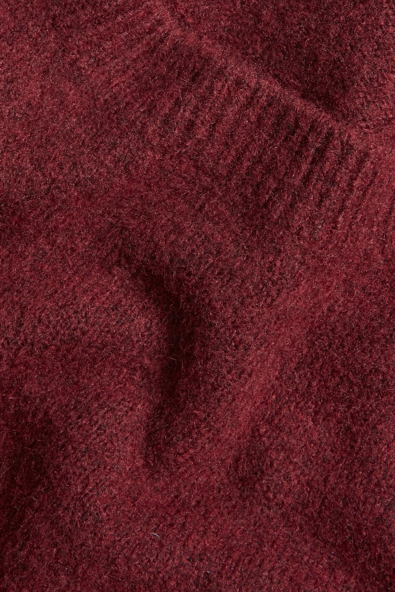 Zbliżenie na melanżową, winnoczerwoną dzianinę, ukazujące jej miękką, teksturowaną powierzchnię.