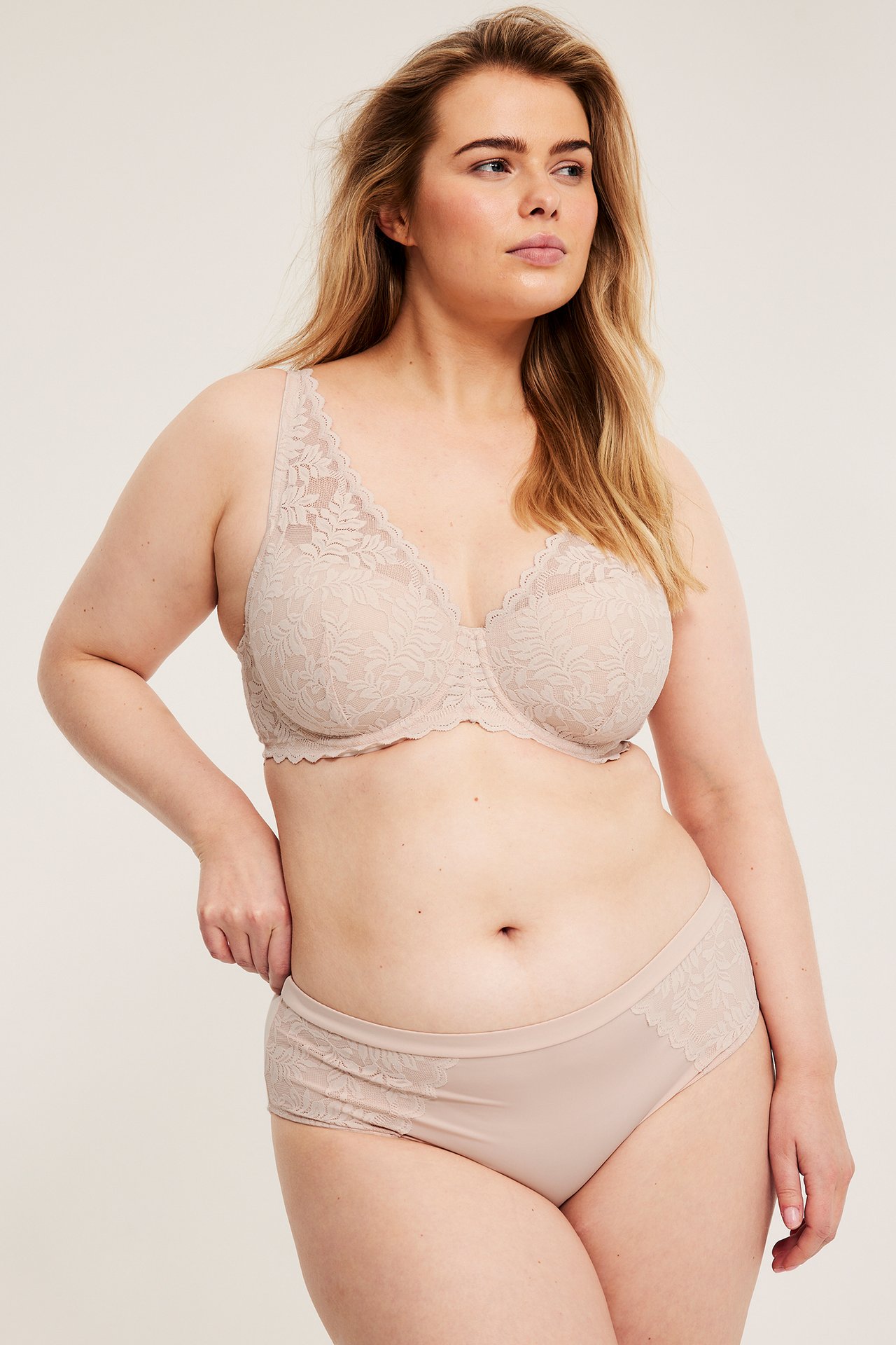 Forfra: kvinne i lyserosa vattert blonde-BH og matchende truse med blonder.