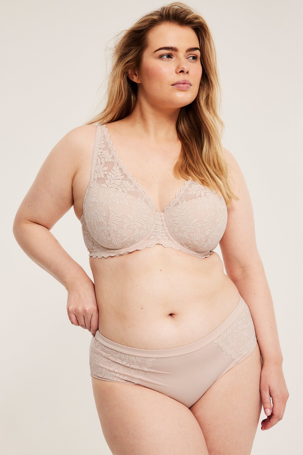 Forfra: kvinne i lyserosa vattert blonde-BH og matchende truse med blonder.