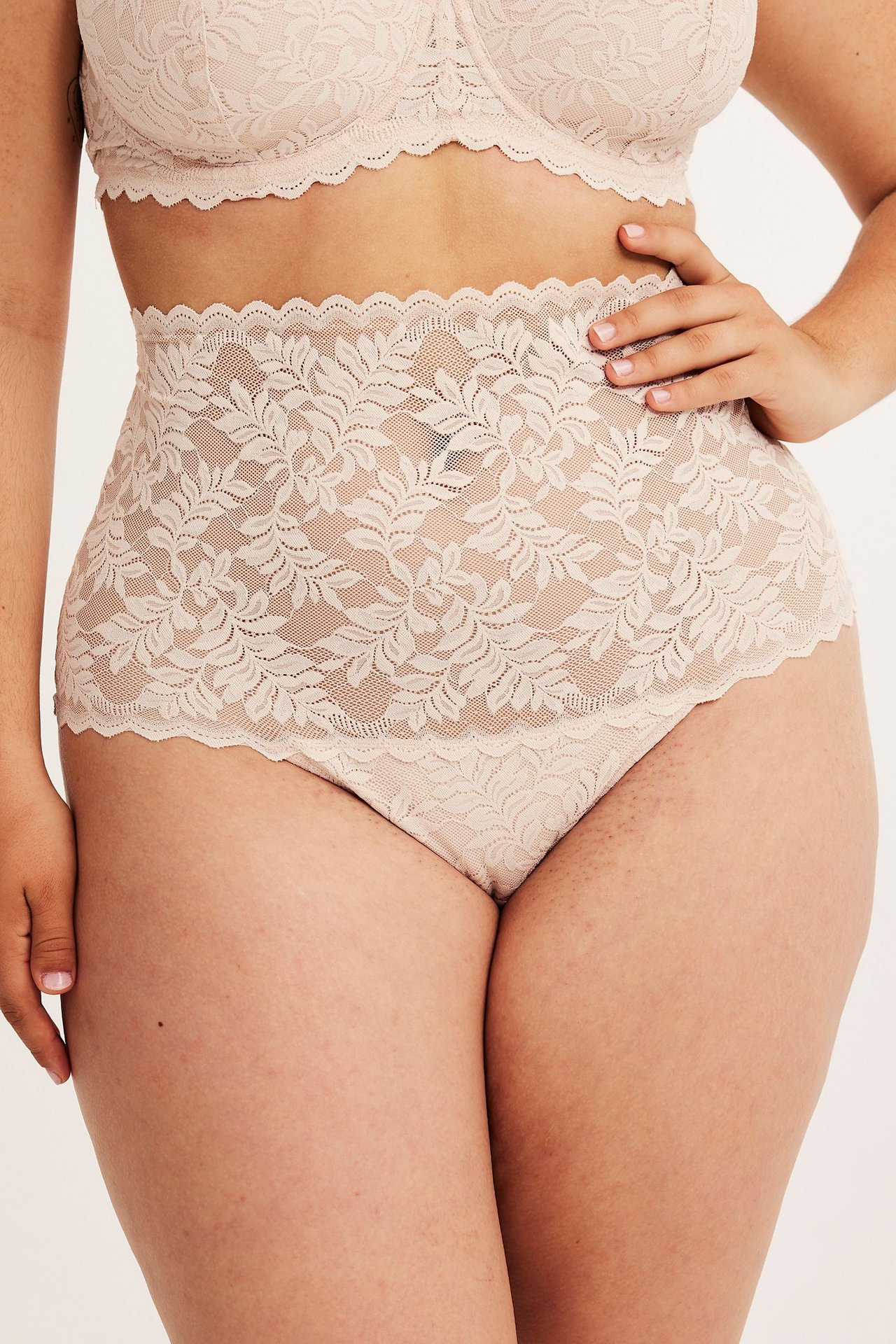 Framifrån, kvinna i ljusrosa hög midja spetstrosa och matchande spets-bh.