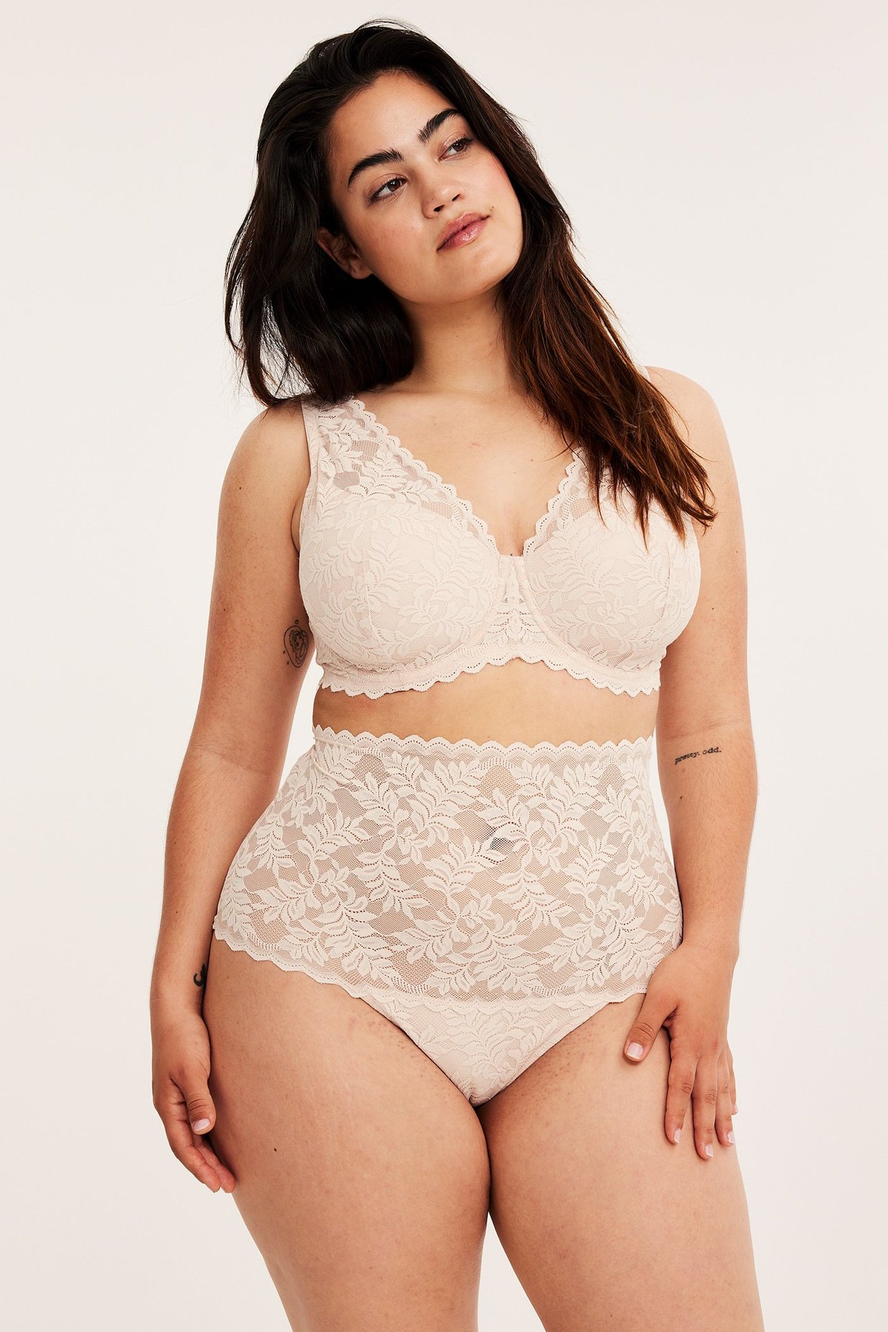 Forfra: kvinne i lys rosa høytlivs blonde truse og matchende blonde-bh.