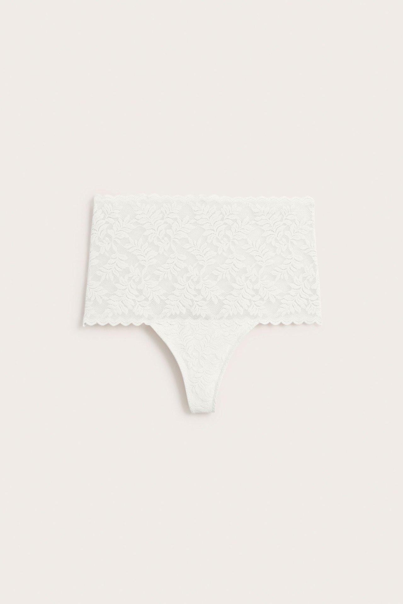 Frontvisning av en offwhite høytlivs blondestring med blomstermønster.