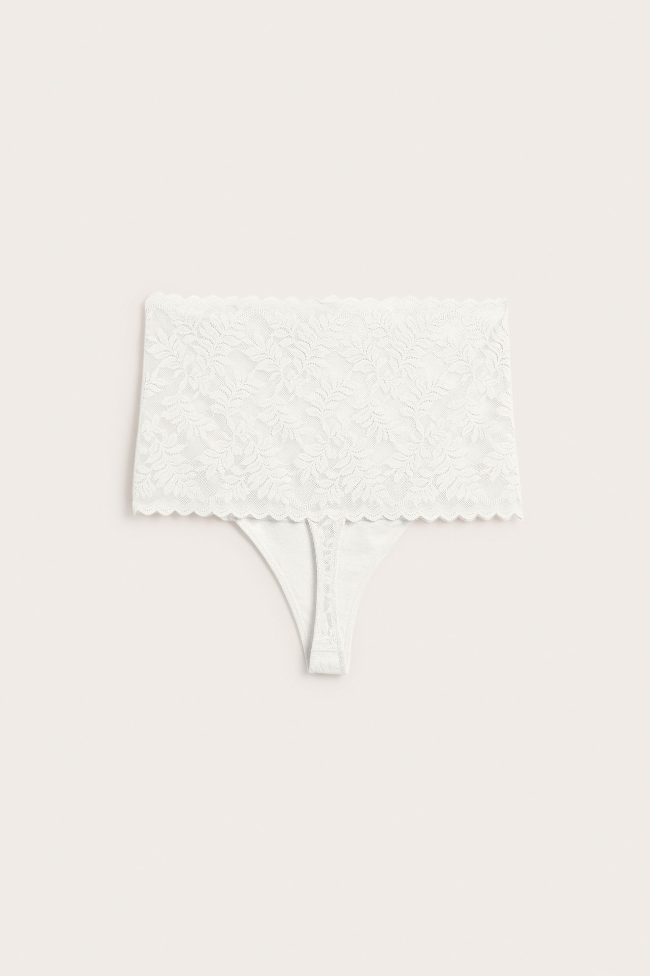 Framifrån, offwhite högmidjad stretchig spetstrosa med blommönster.