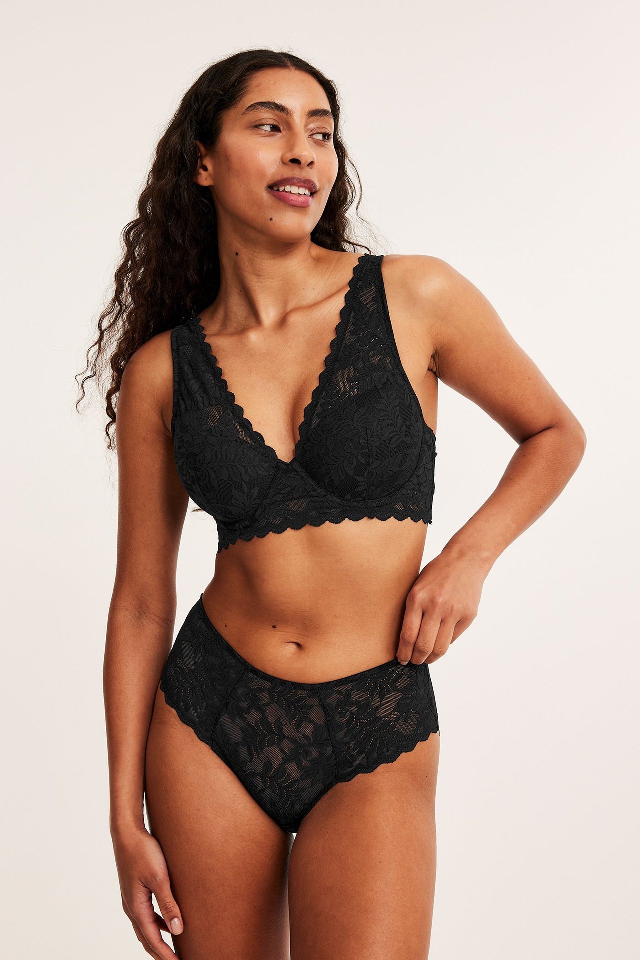 Forfra, kvinne i svart vattert blonde-BH og matchende svarte blonde-truser.