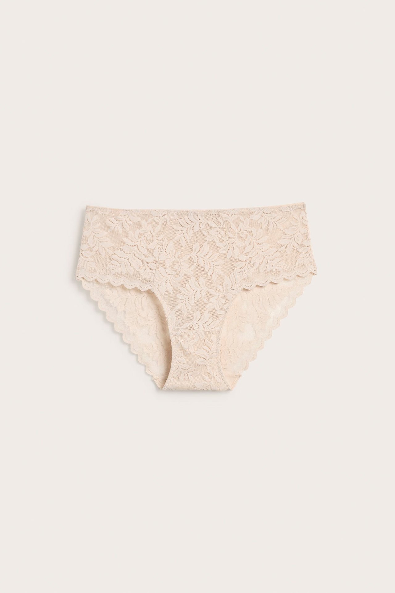 Framifrån, beige spetstrosor för dam med blommönster och vågiga kanter.