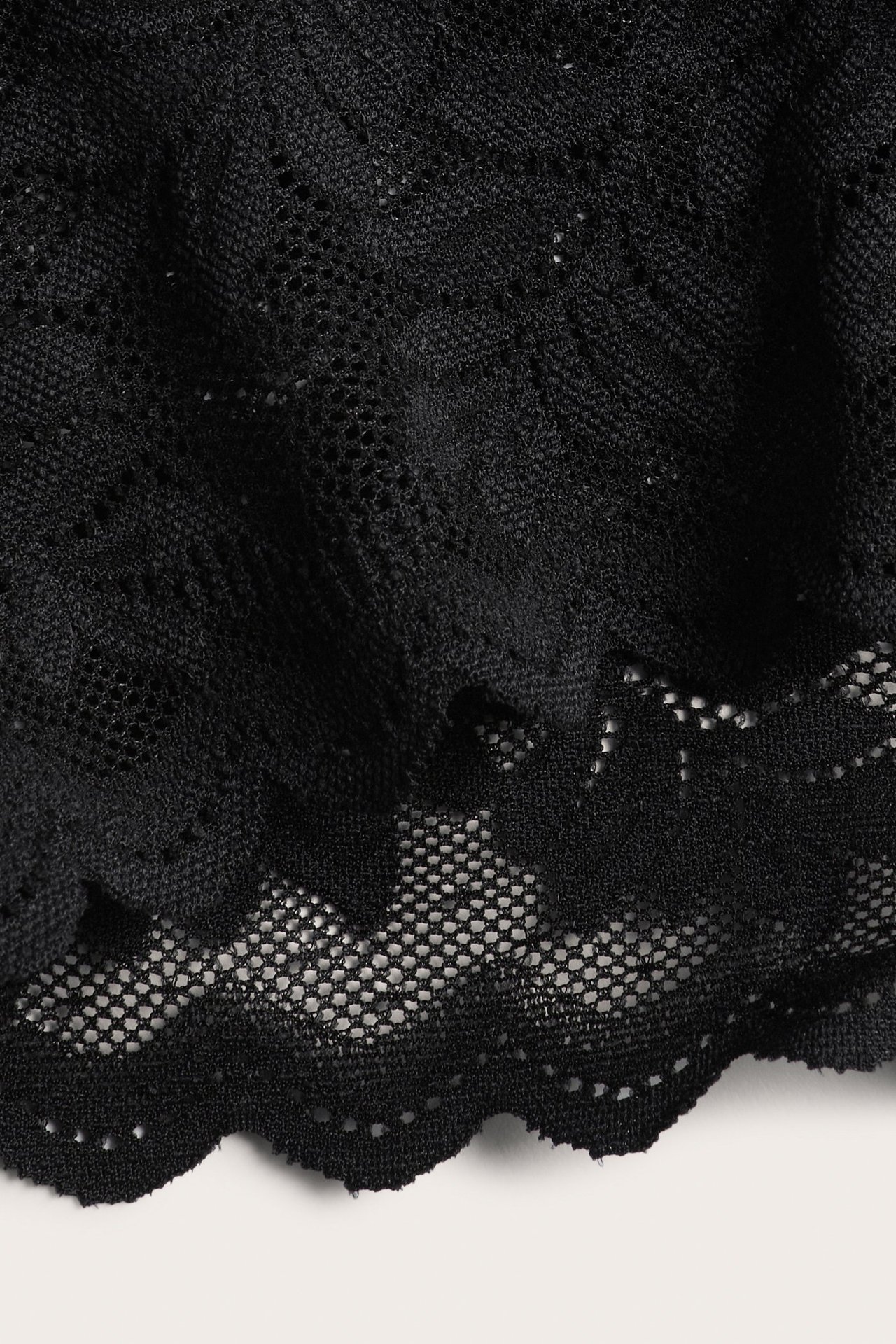 Zbliżenie czarnej koronki z delikatnym wzorem i falistym brzegiem.