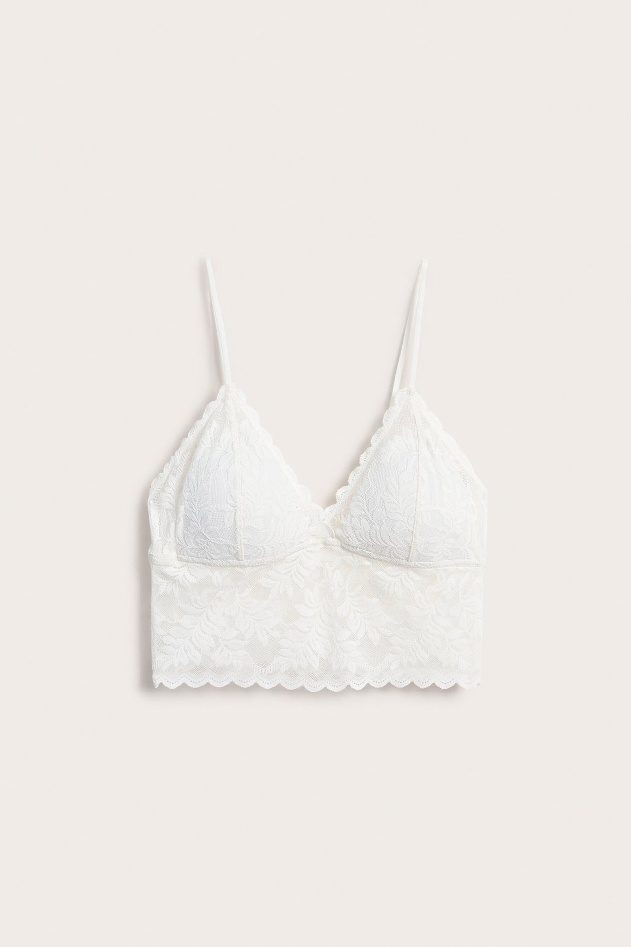 Forfra, offwhite blonde-BH-topp med tynne stropper og en bølget kant.