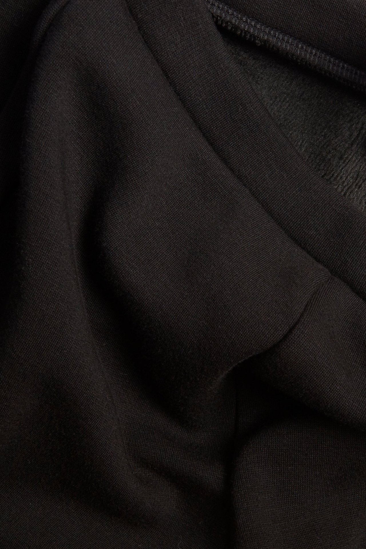 Zbliżenie czarnego, ocieplanego materiału legginsów, ukazujące jednolity splot i szczotkowane wnętrze.