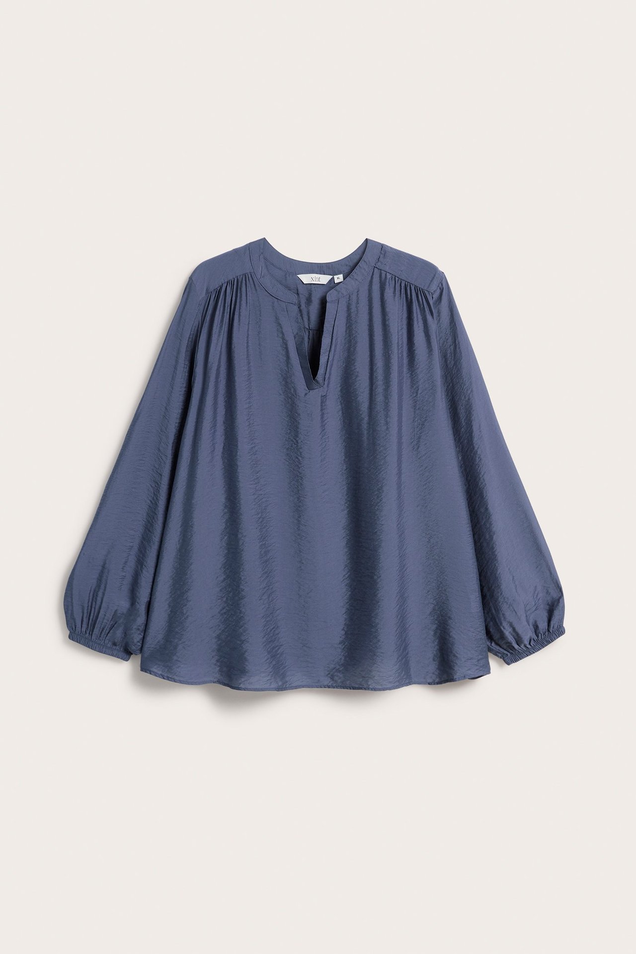 Widok z przodu luźnej, niebieskiej bluzki z teksturą, dekoltem w serek i długimi rękawami z gumką.