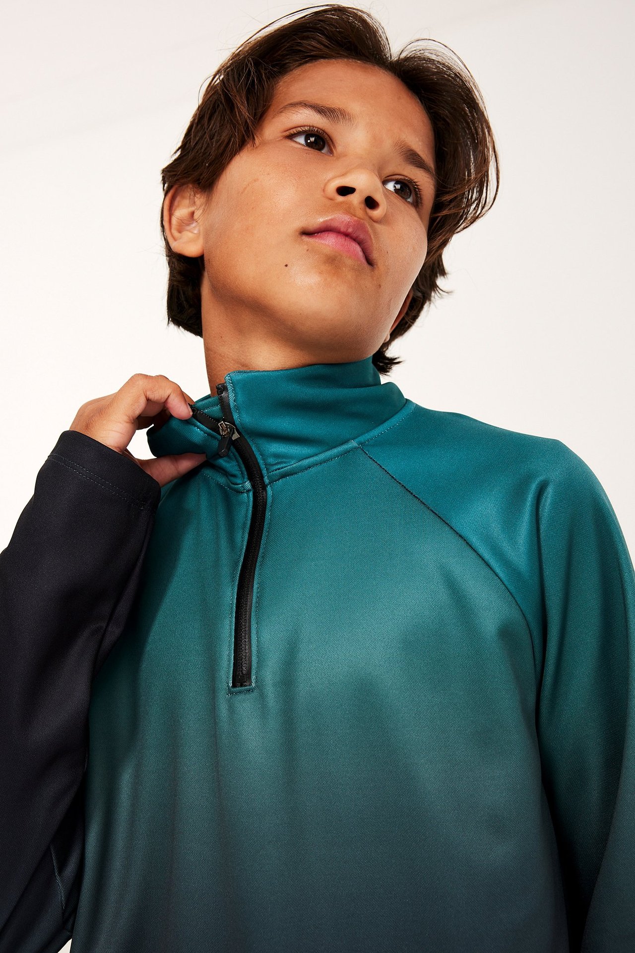 Zbliżenie dziecka w bluzie treningowej dip-dye, turkusowej do ciemnozielonej, z czarnym półzamkiem i rękawami.