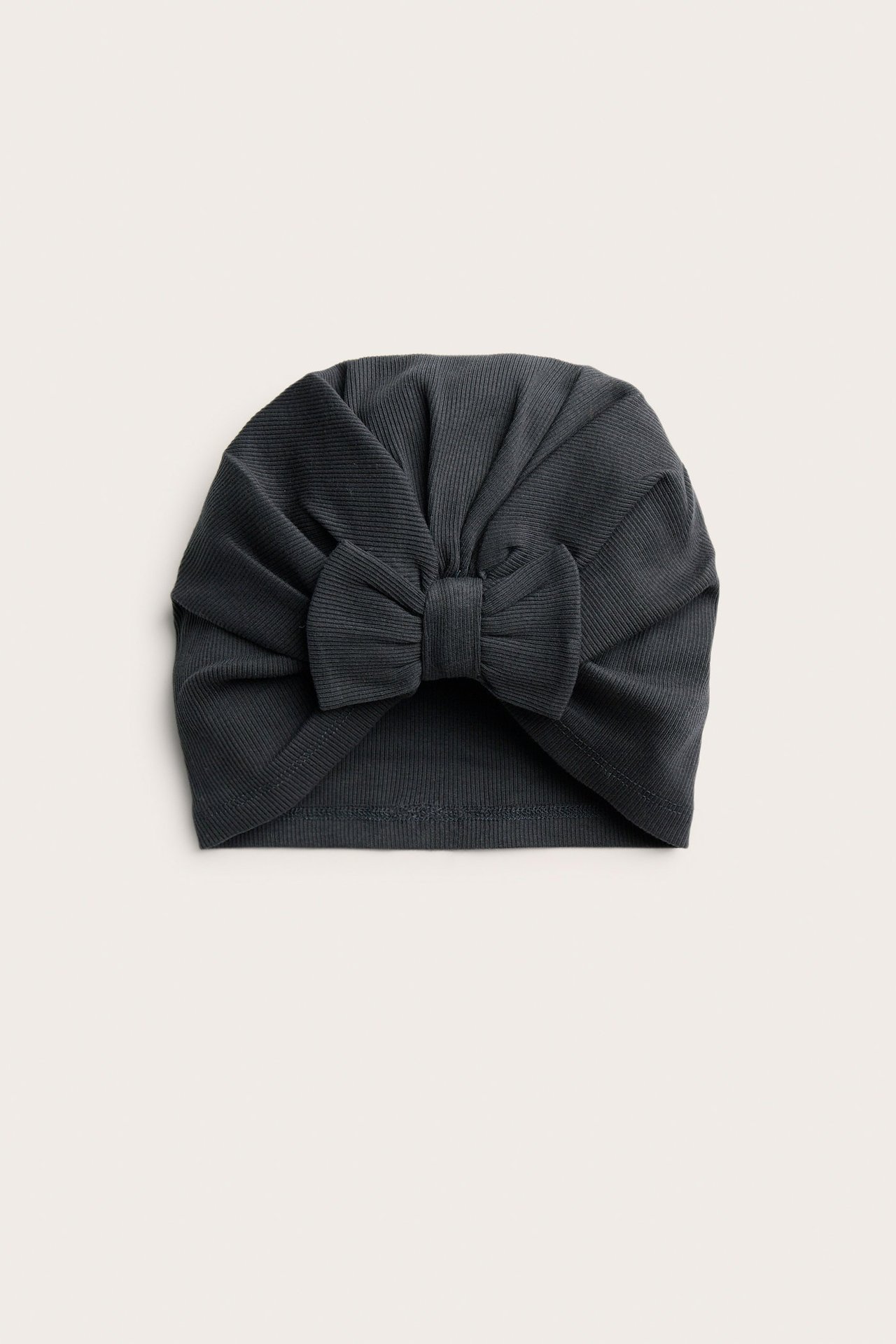 Edestä näkymä mustasta ribatusta vauvan piposta, jossa on koristeellinen rusetti edessä.