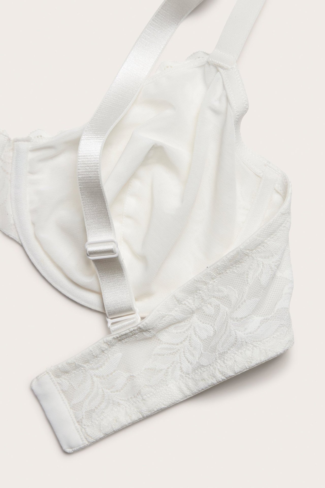 Zbliżenie, widok z góry, na biustonosz z fiszbinami w kolorze ecru, wykonany z elastycznej koronki.