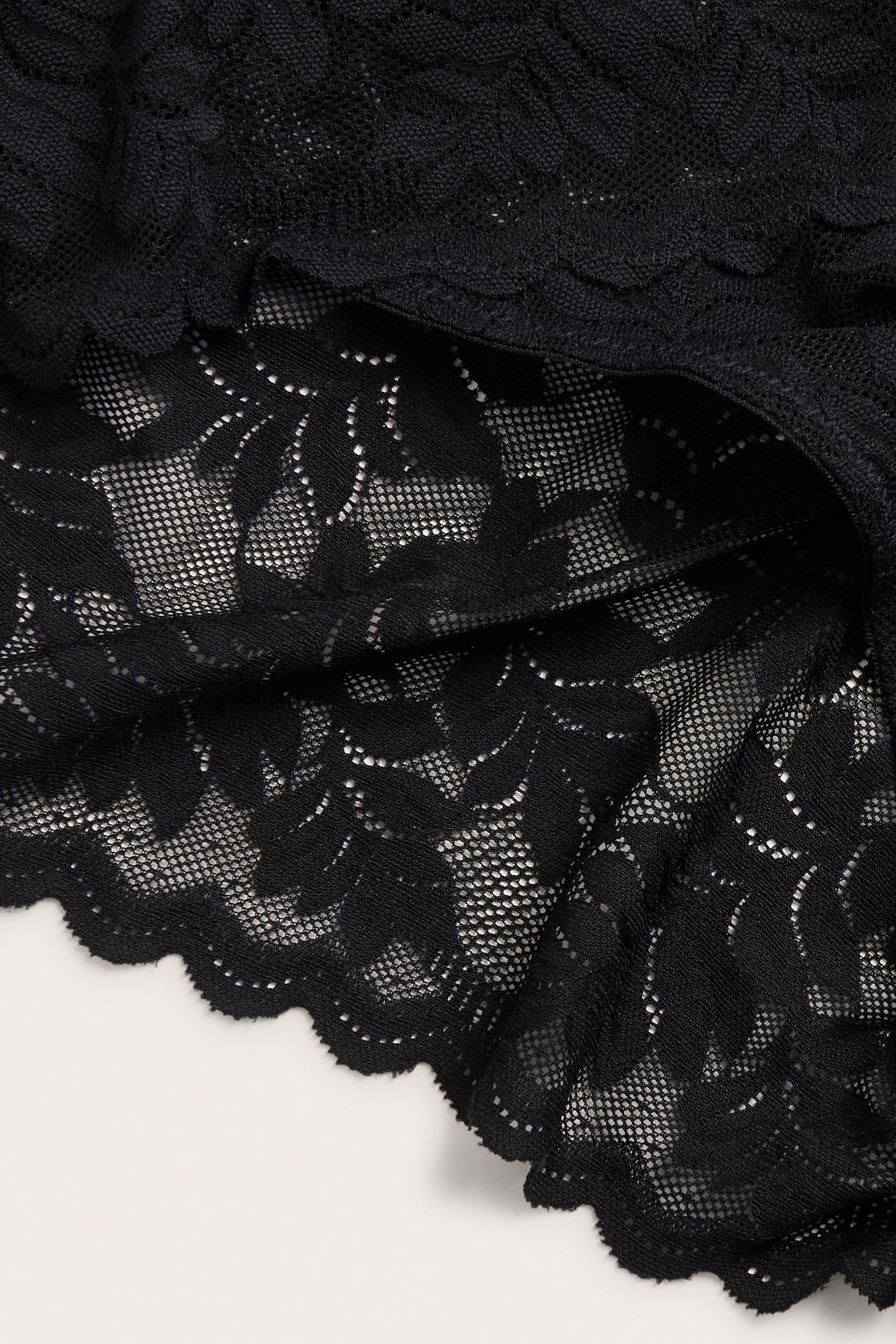 Zbliżenie czarnych koronkowych fig cheeky z kwiatowym wzorem.