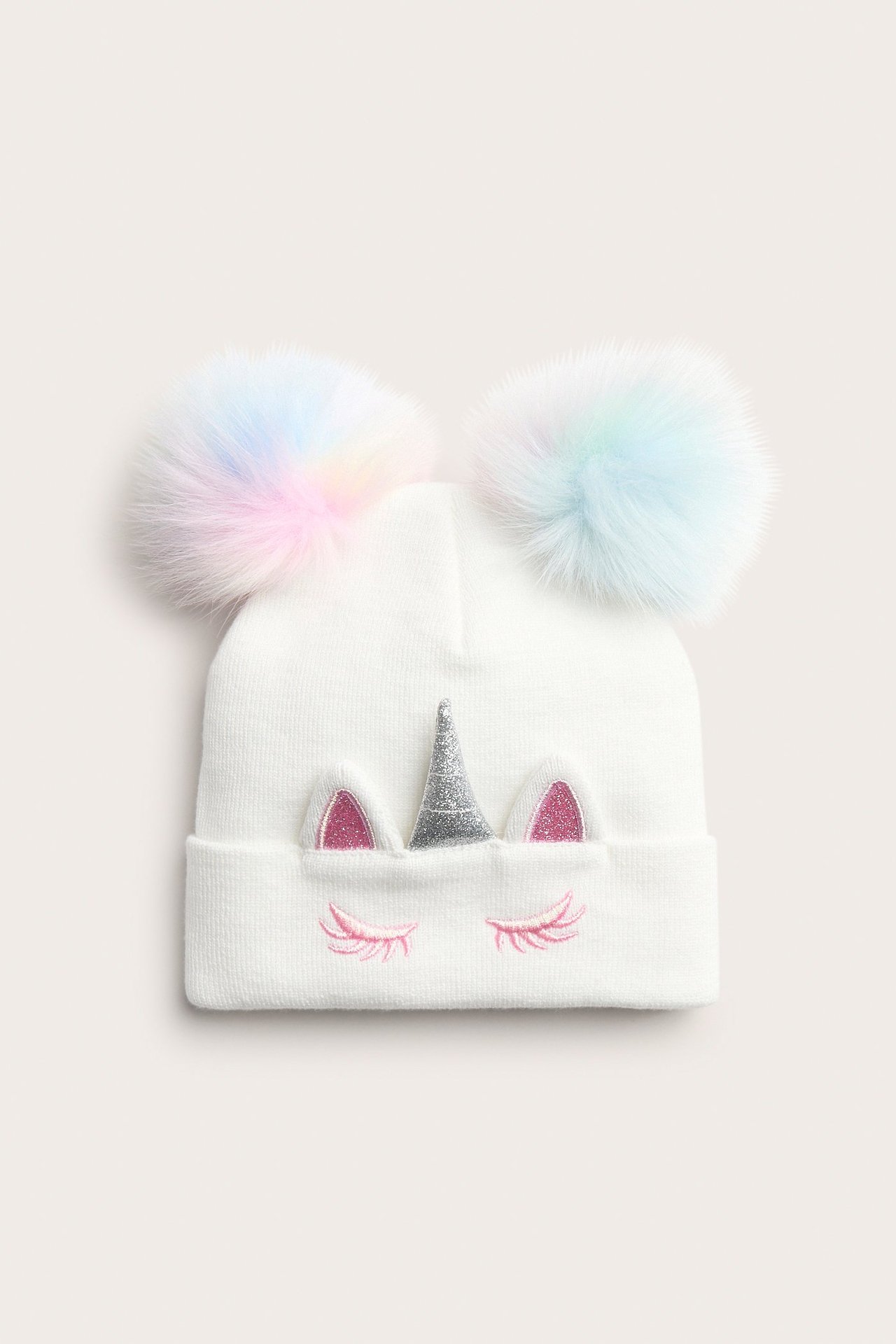 Edestä: Lasten luonnonvalkoinen neulottu pipo, moniväriset tupsut, hopeinen yksisarvisen sarvi, vaaleanpunaiset korvat, brodeeratut ripset.